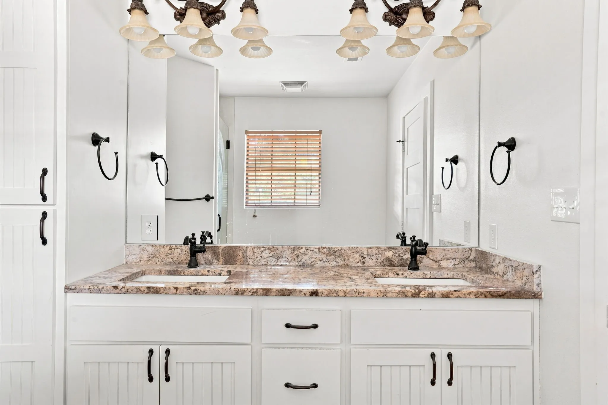 Dual vanity with integrated sinks, speckled countertop, and white cabinetry