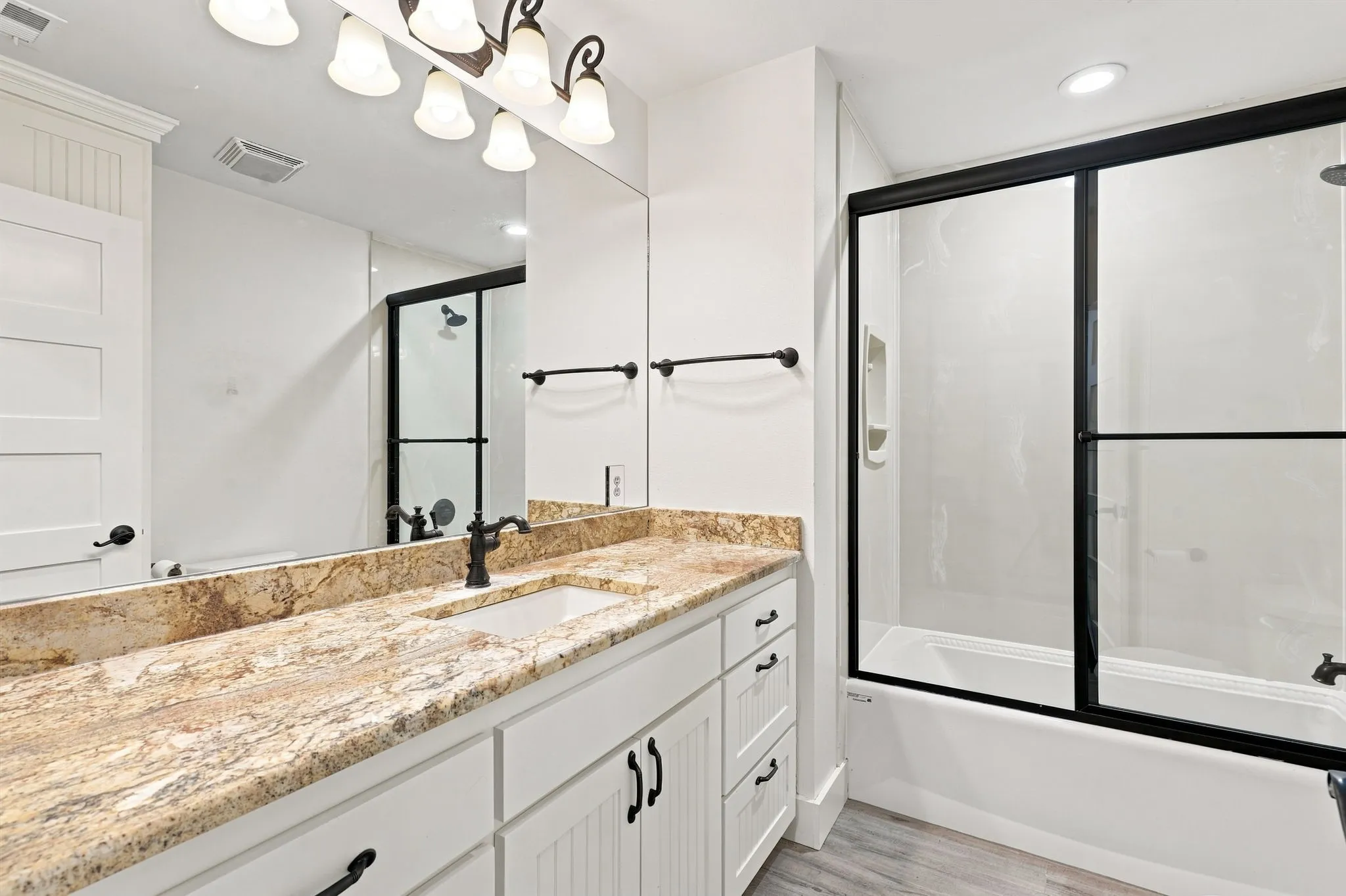 Bathroom vanity featuring a light-toned countertop, undermount sink, and dark-finished faucet