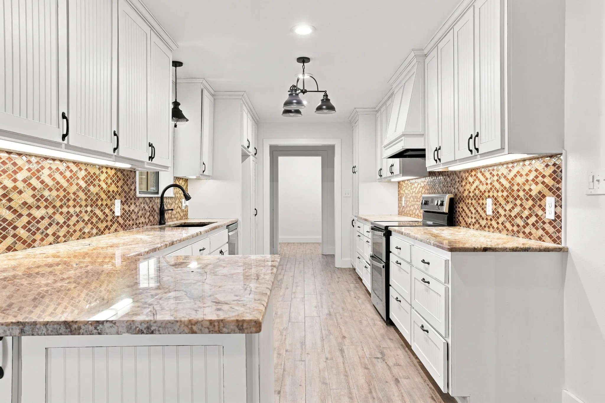 Galley kitchen featuring white cabinetry, mosaic tile backsplash, granite countertops, wood-finish flooring, and a double wall oven