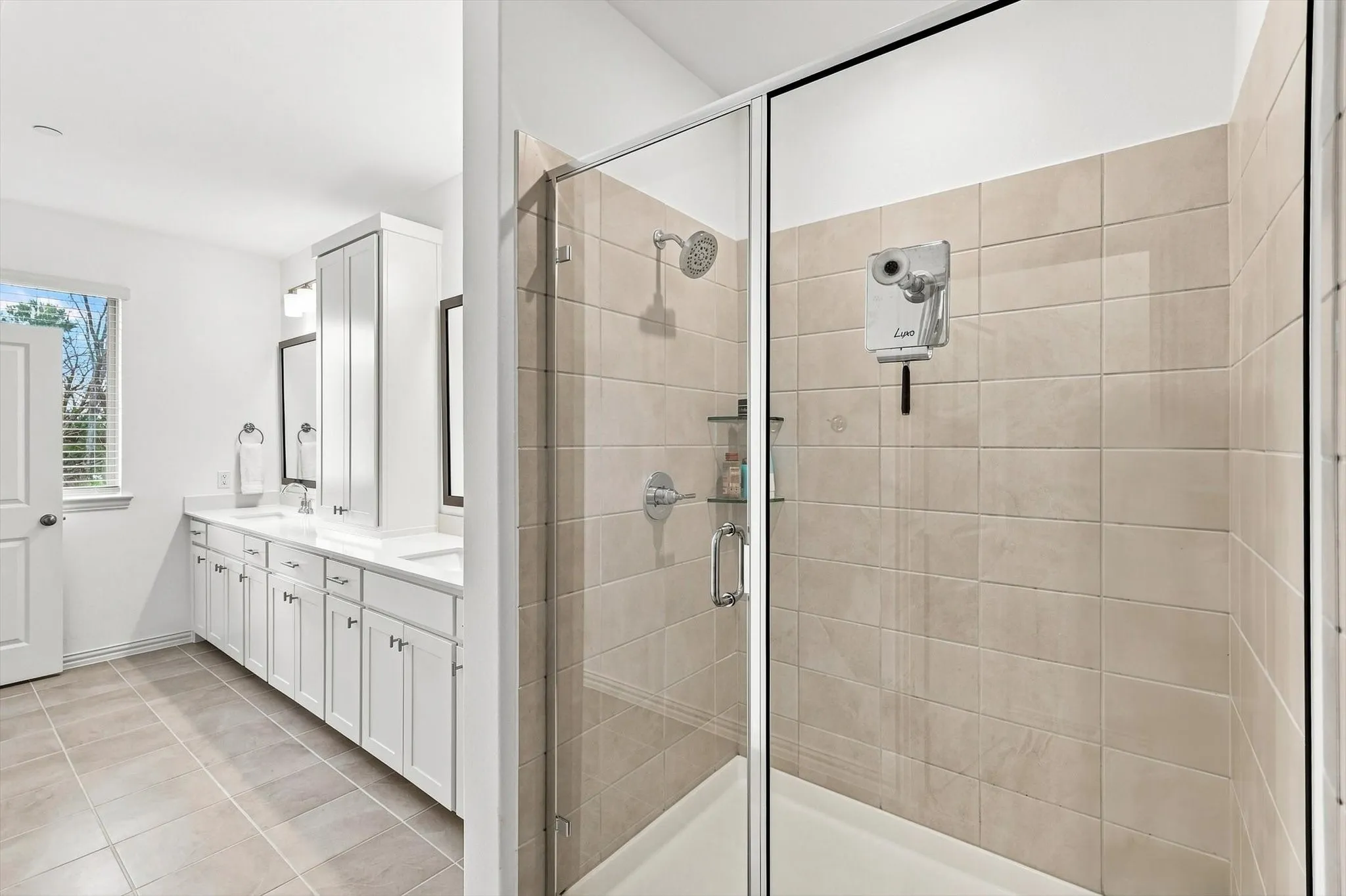 A relaxing finish to the primary suite. The spacious glass-enclosed shower features neutral tile and a clean, timeless design.