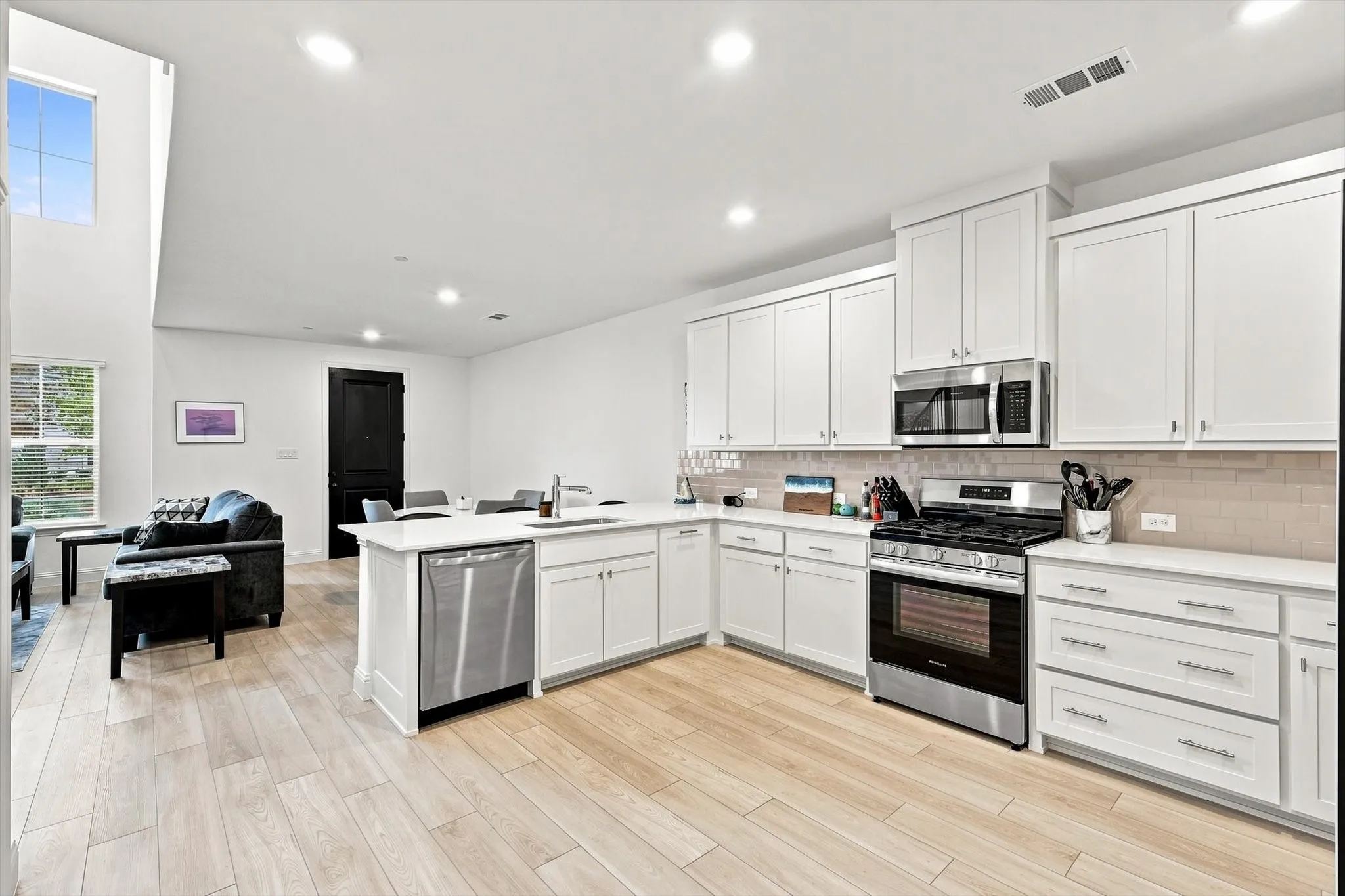 Bright, polished, and effortlessly inviting. Crisp white cabinetry, stainless appliances, generous prep space, and seamless flow into the living area make this kitchen a standout.
