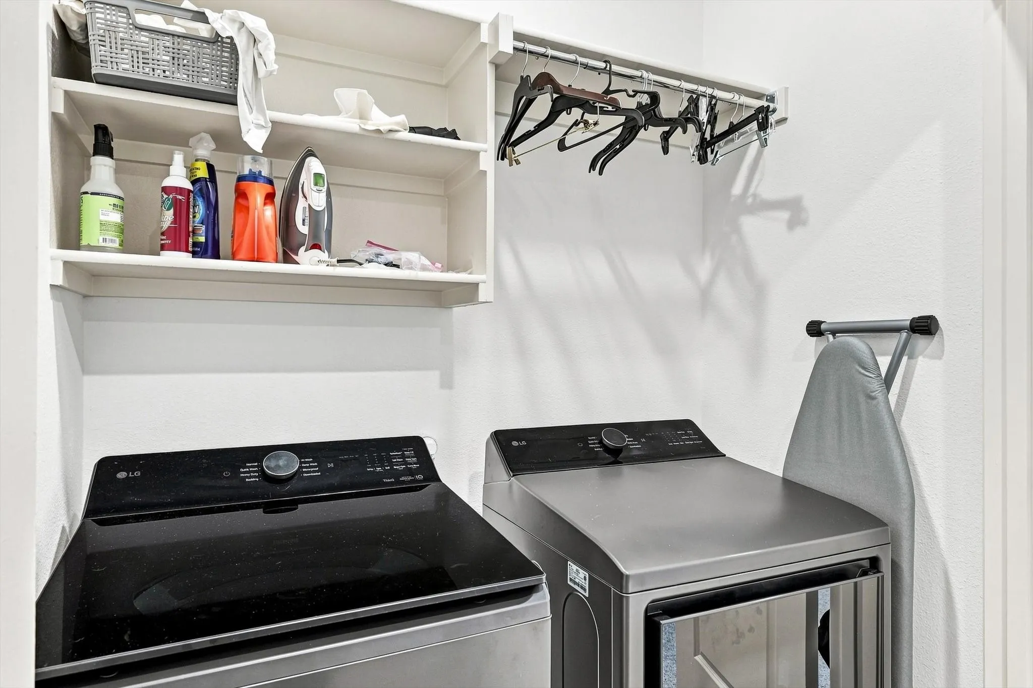 Smart storage makes this laundry area exceptionally functional, with shelving, hanging space, and room to keep everything neatly organized.