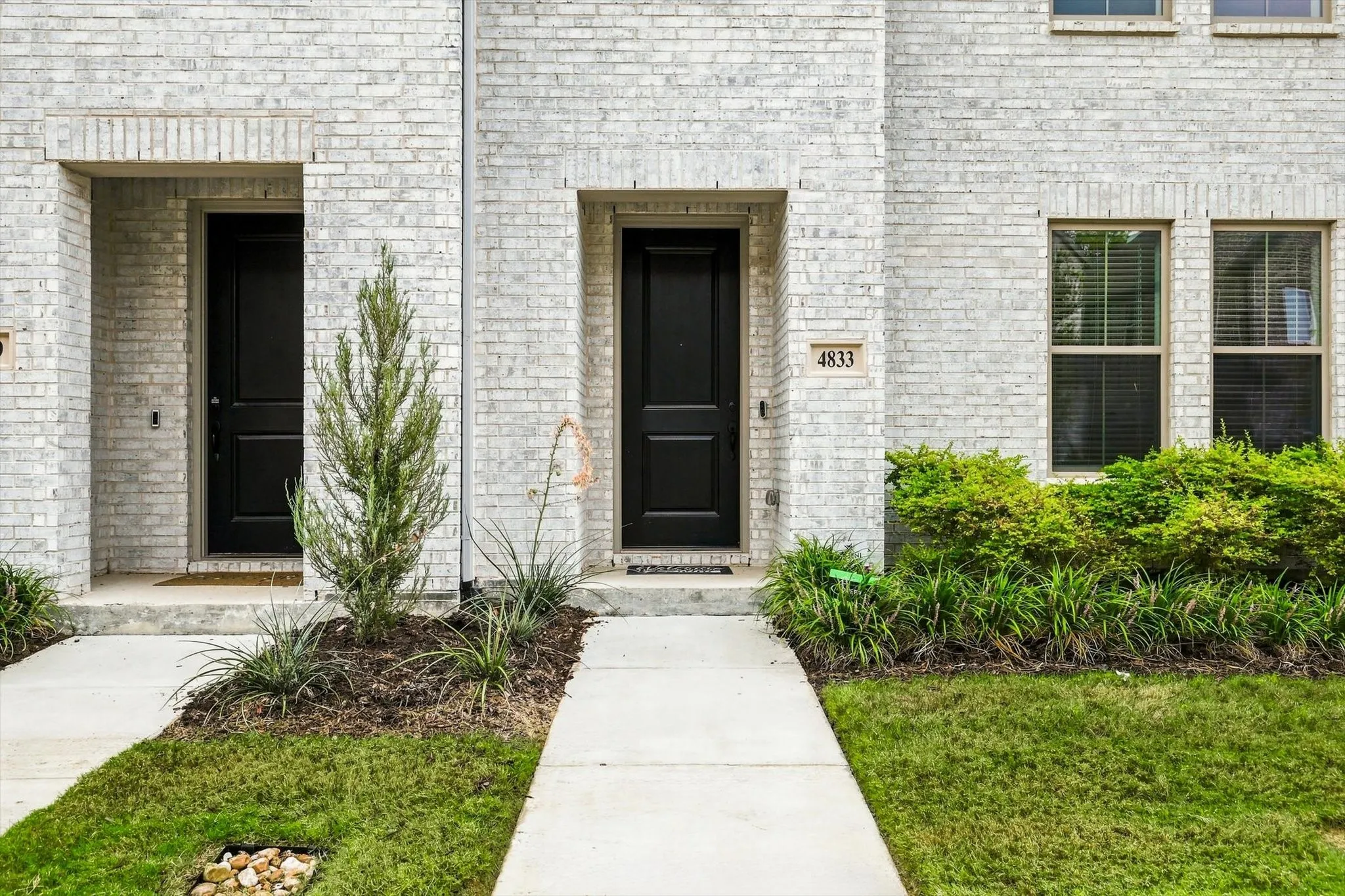 Welcome home. The bold black entry door against classic white brick creates a timeless, sophisticated entrance.