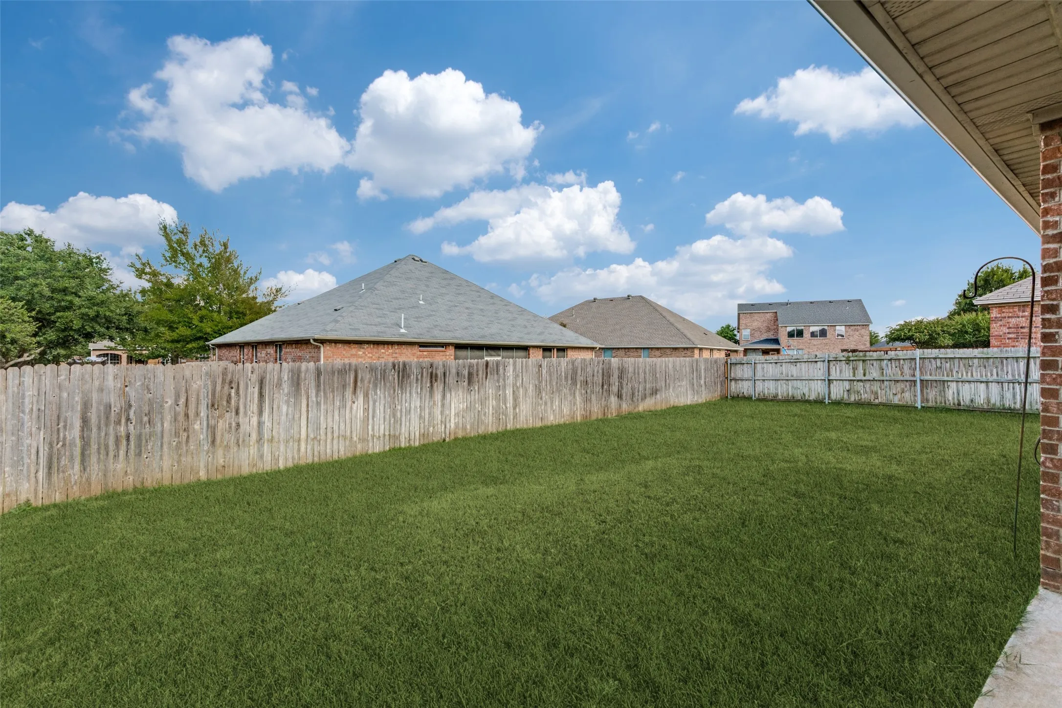 Expansive grass lawn enclosed by a wood privacy fence