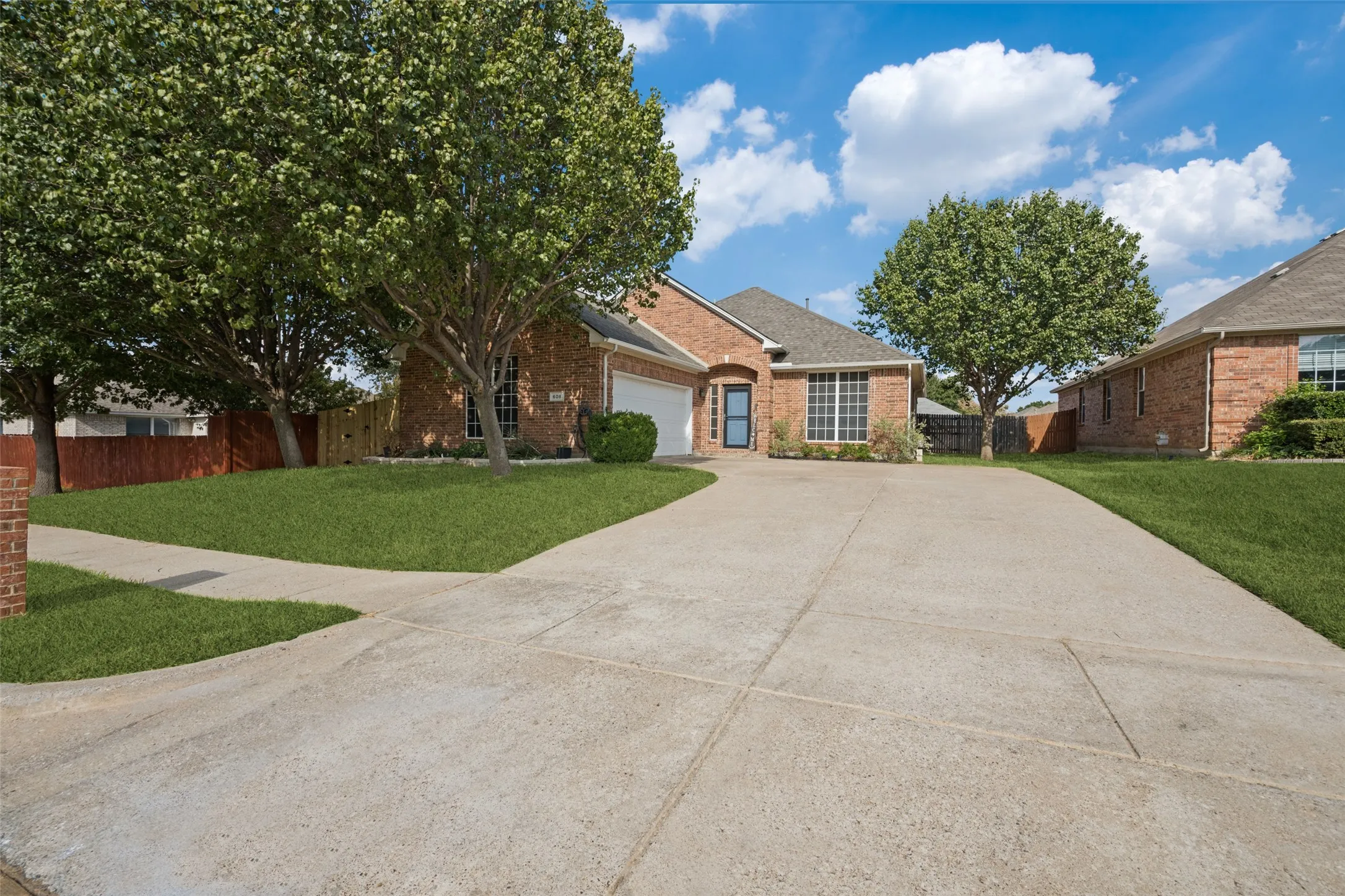 Brick exterior, concrete driveway, attached garage, mature trees, manicured lawn