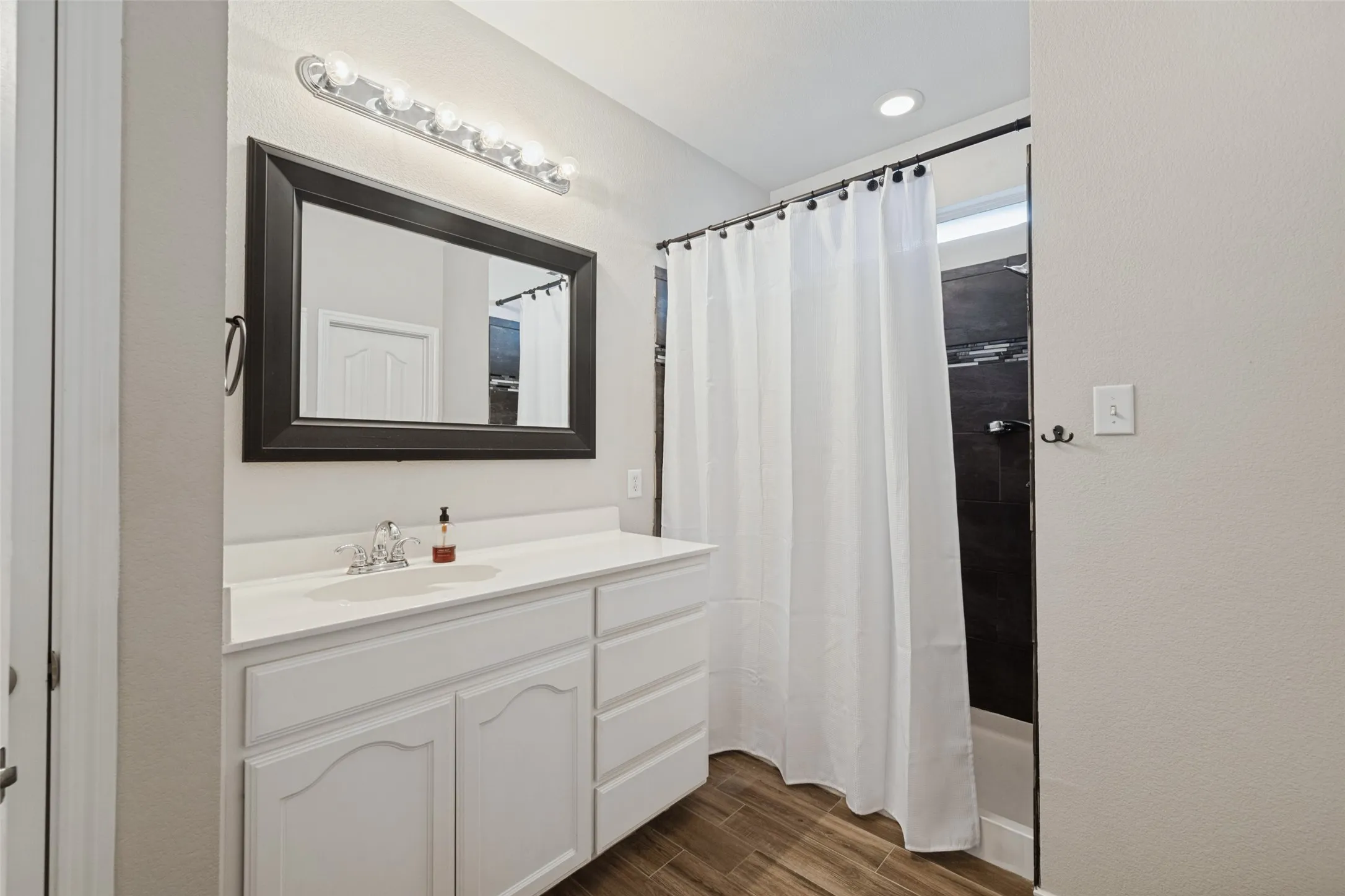 White vanity with a single basin sink, chrome faucet, and a framed mirror