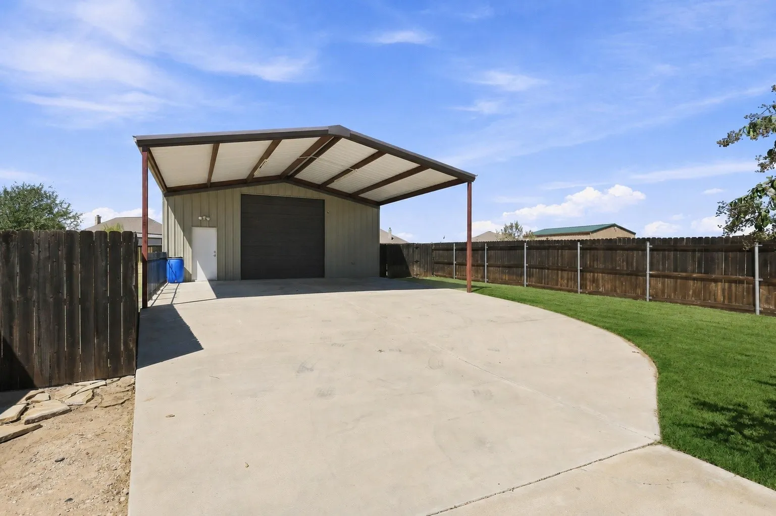 Grass is digitally enhanced. 30x40 Red Iron Welded Workshop with Carport, 12ft Overhead Door, RV Plug and 100amp Service. A Really Nice Building!