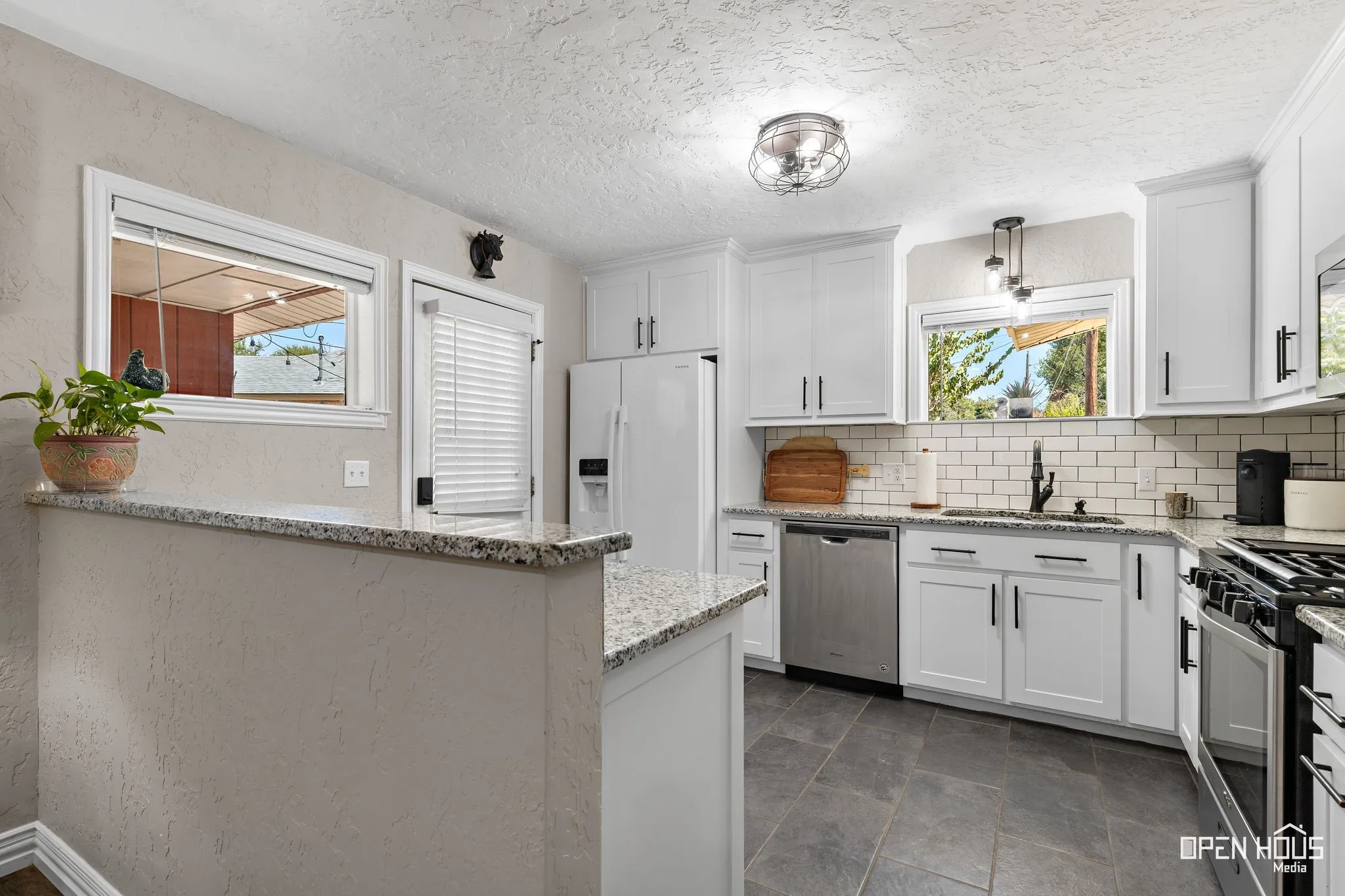 Kitchen featuring white shaker-style cabinetry, granite countertops, stainless steel appliances, and a subway tile backsplash