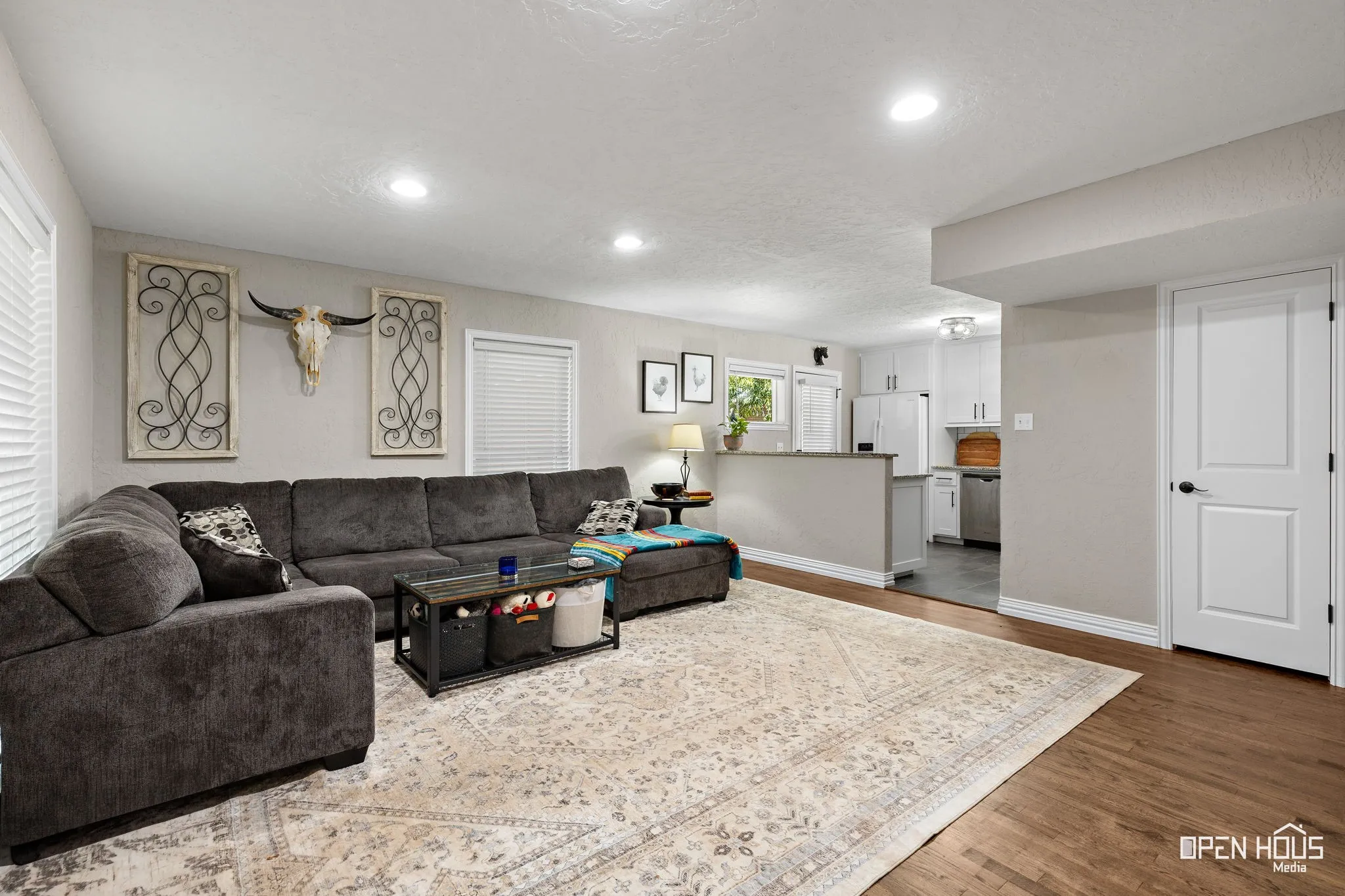Recessed lighting illuminates the living area with wood-finish flooring