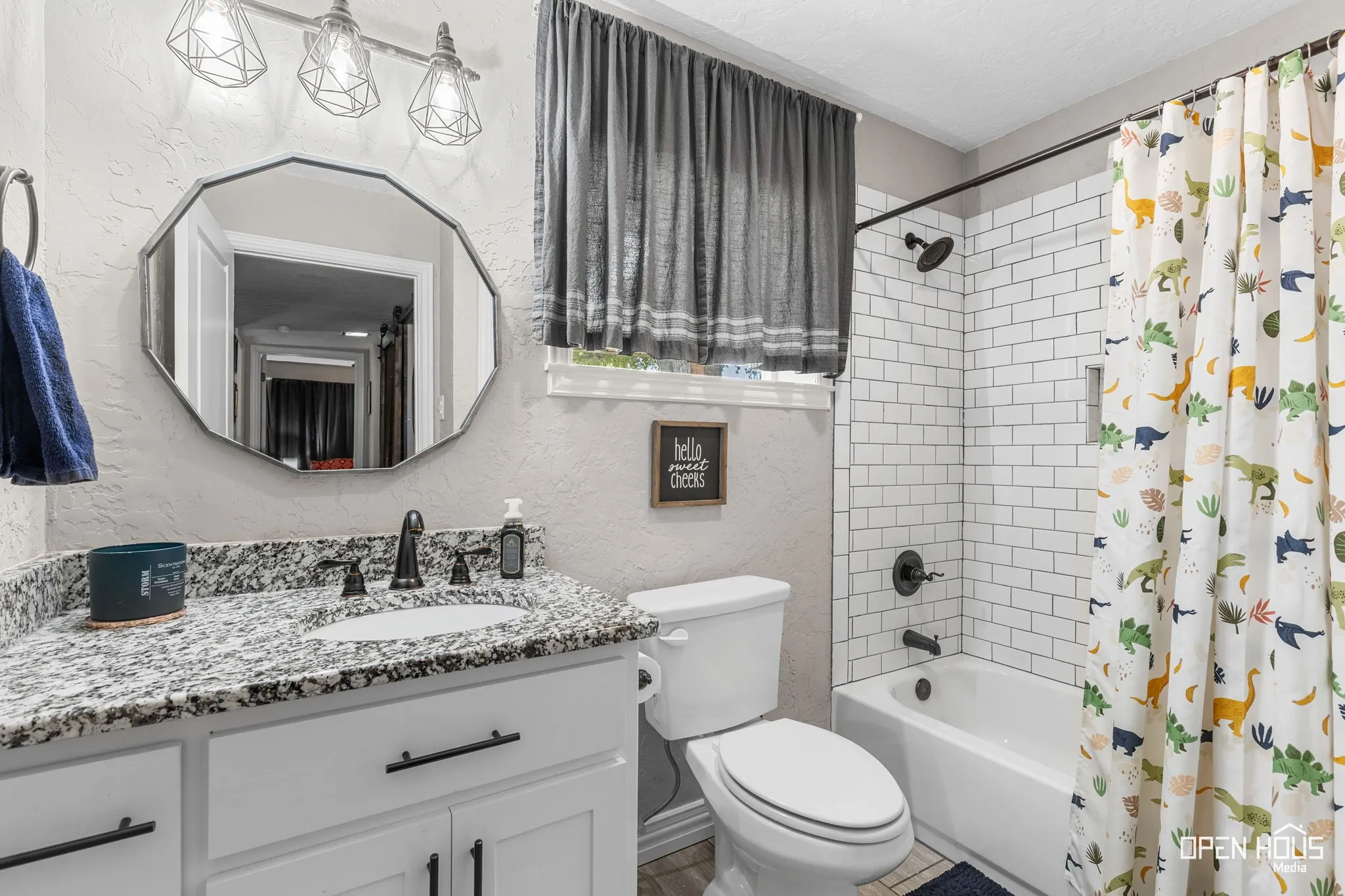 White vanity with dark pulls, speckled countertop, and black faucet