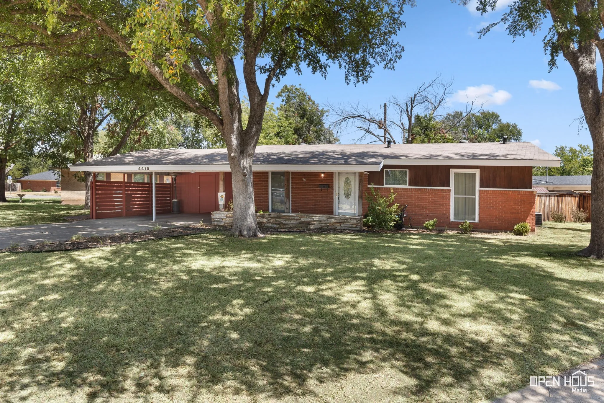 Brick exterior with wood paneling, a covered carport, and a stone-clad entry