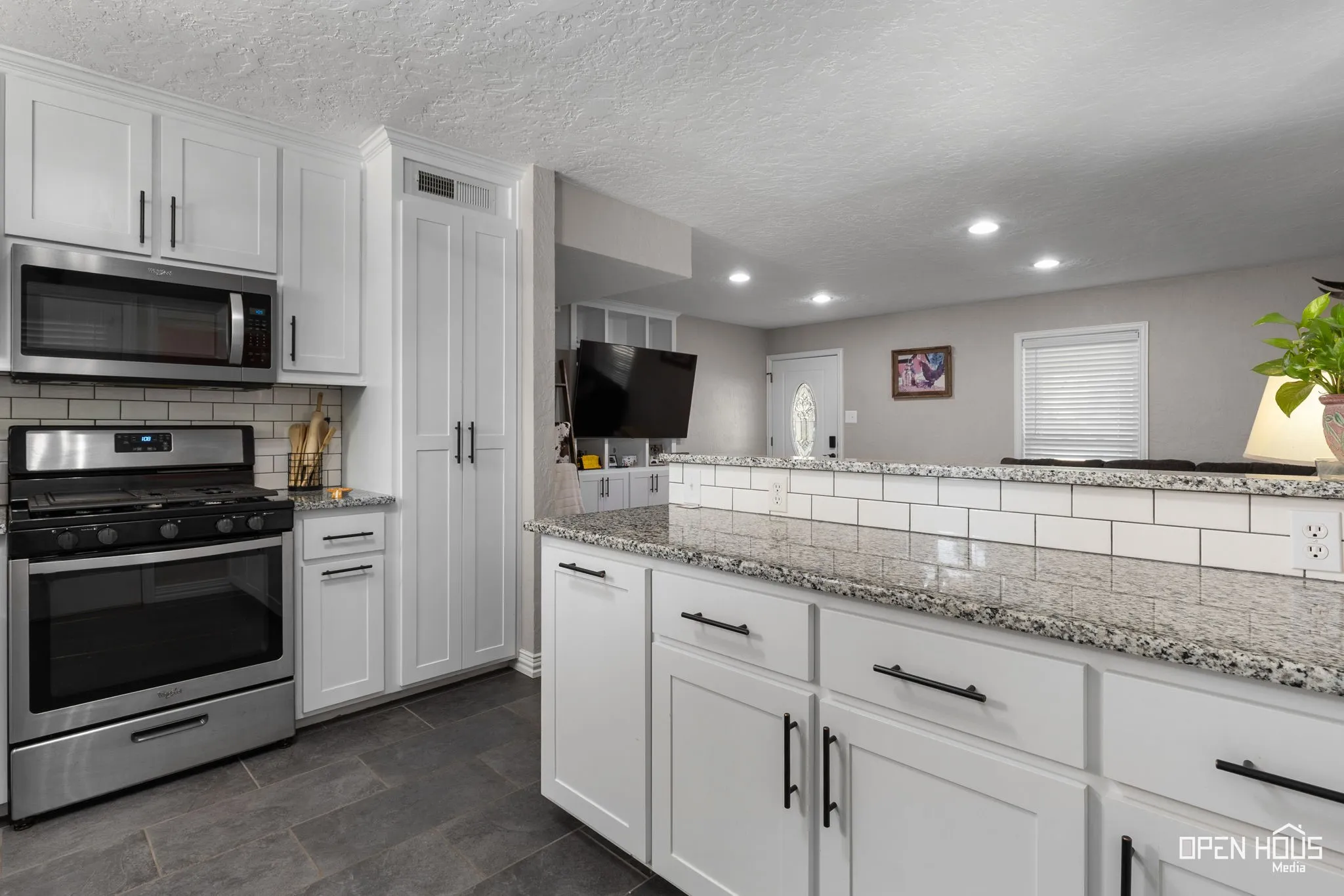 Kitchen featuring white cabinetry, stainless steel appliances, speckled countertops, and a subway tile backsplash