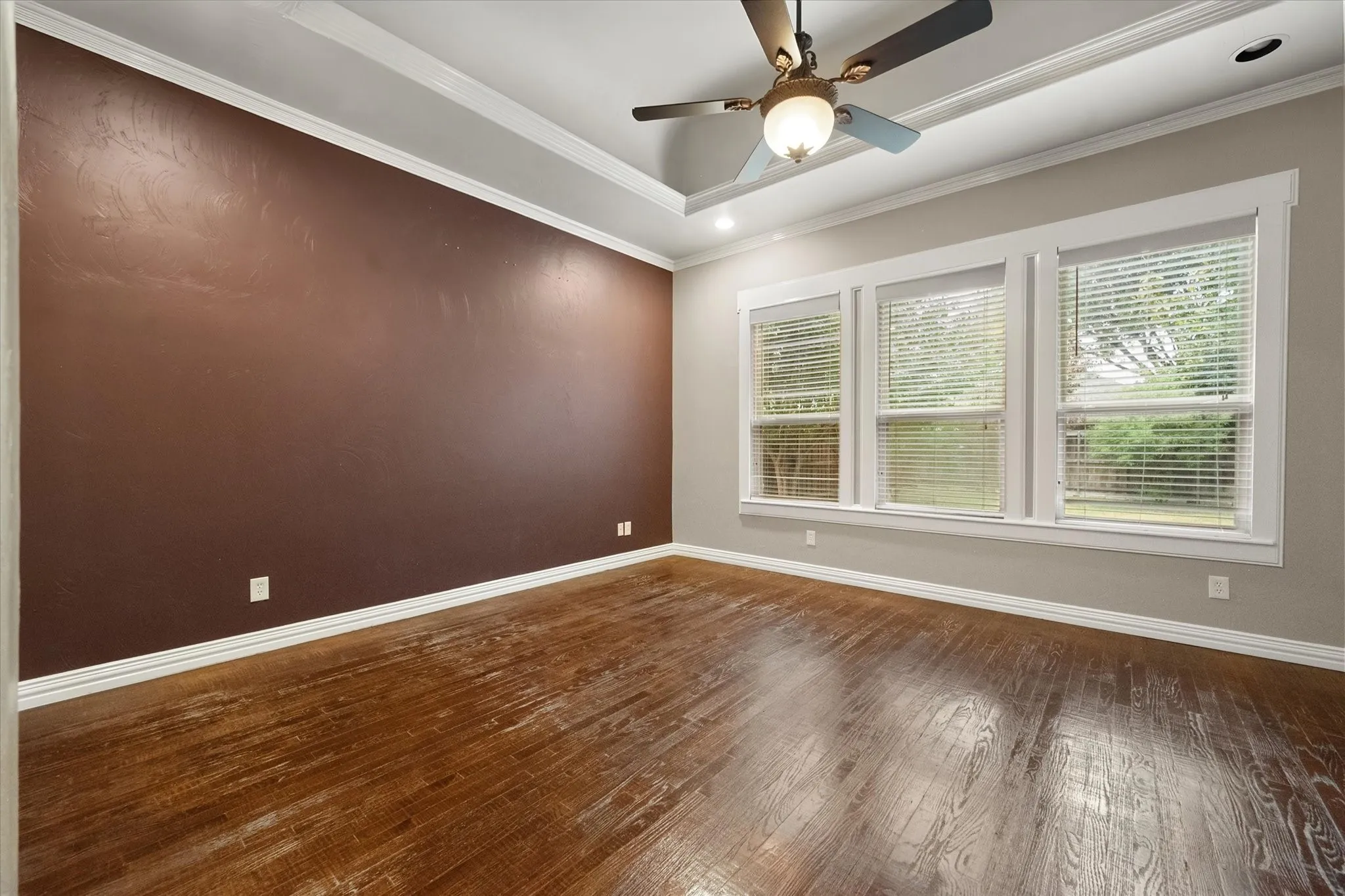 Primary bedroom with wood floor, extensive wood trim and vaulted ceiling