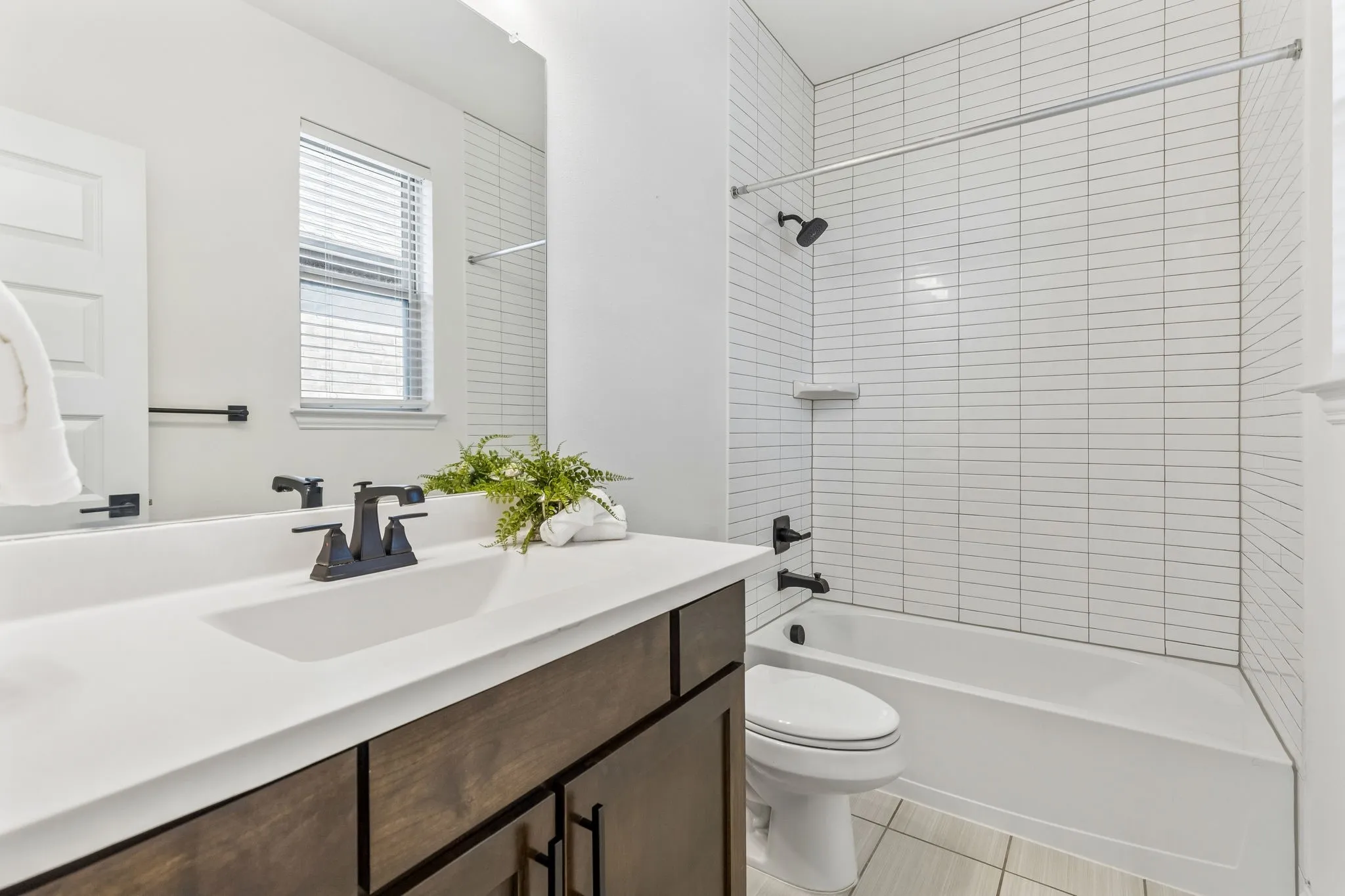Bathroom featuring a single vanity with dark wood-finish cabinetry, solid surface countertop, and matte black fixtures