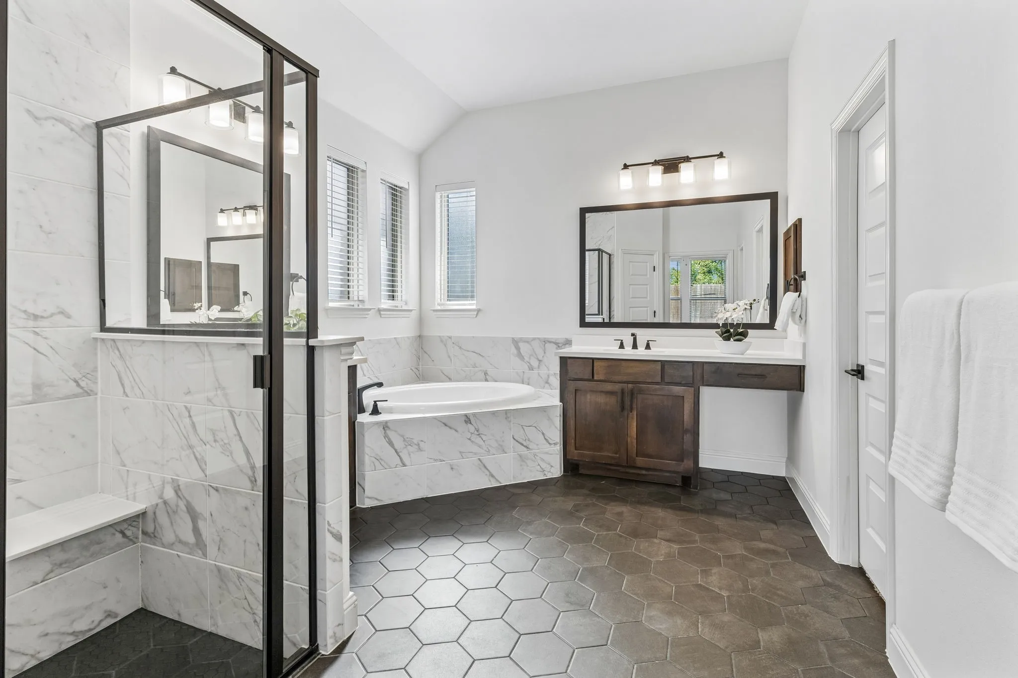 Tiled walk-in shower with a built-in bench and dark-framed glass enclosure