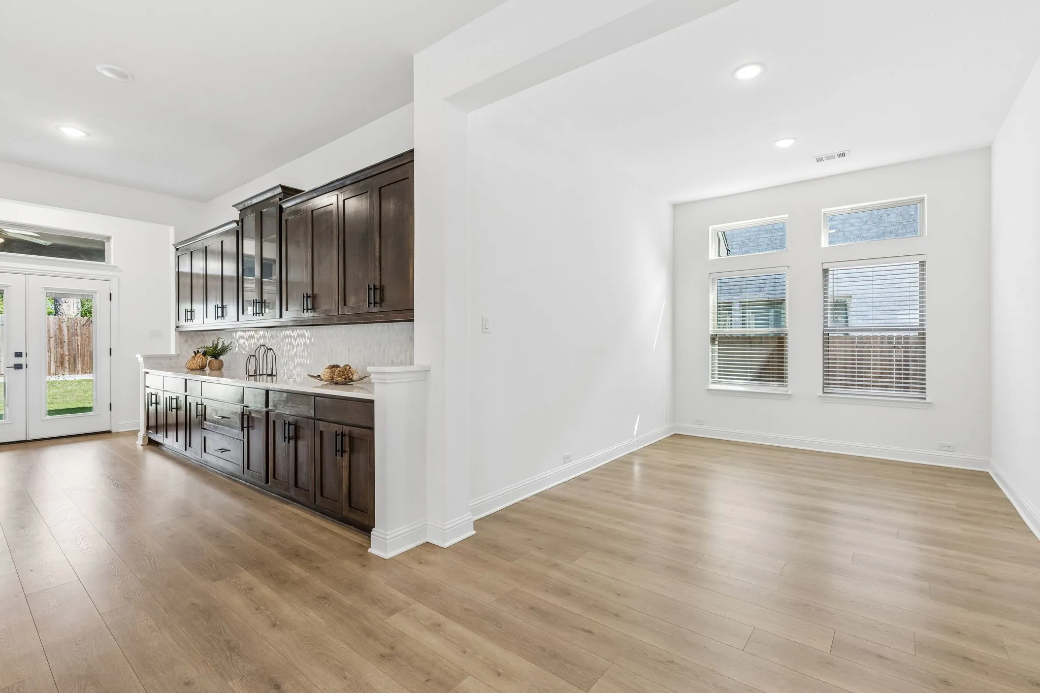 Wood-finish flooring throughout, with a built-in cabinetry unit featuring a white countertop and tile backsplash
