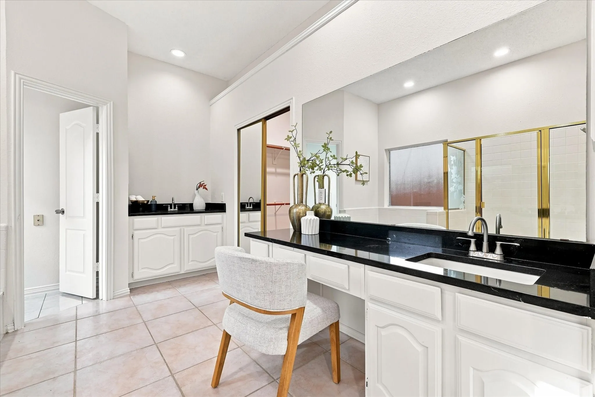 Sleek black granite and dual vanities add a stylish, modern touch to this inviting primary bath.