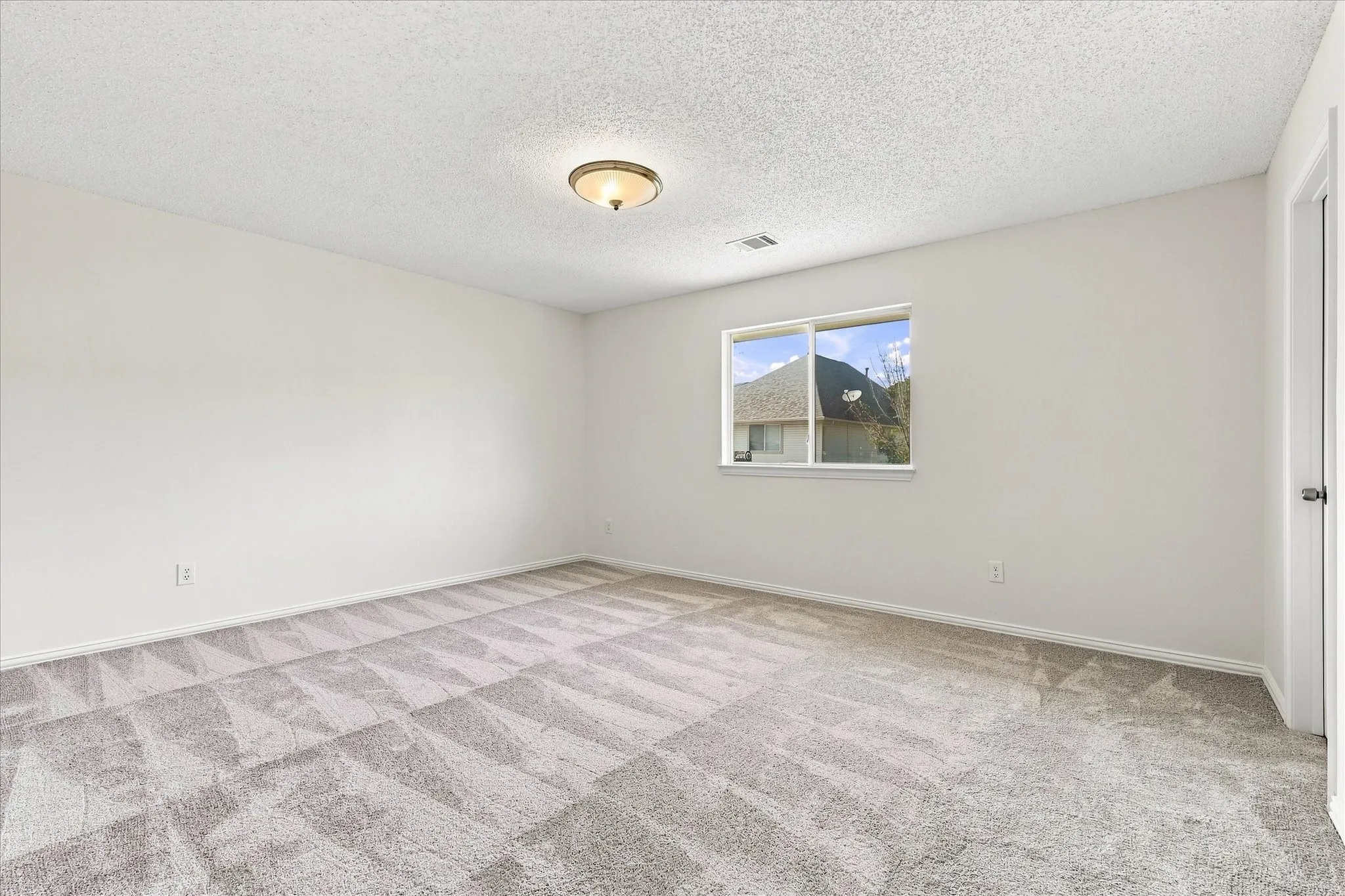 The same spacious upstairs bedroom shown without virtual staging, giving you a better feel for the space and a blank canvas to envision how you’d style it.