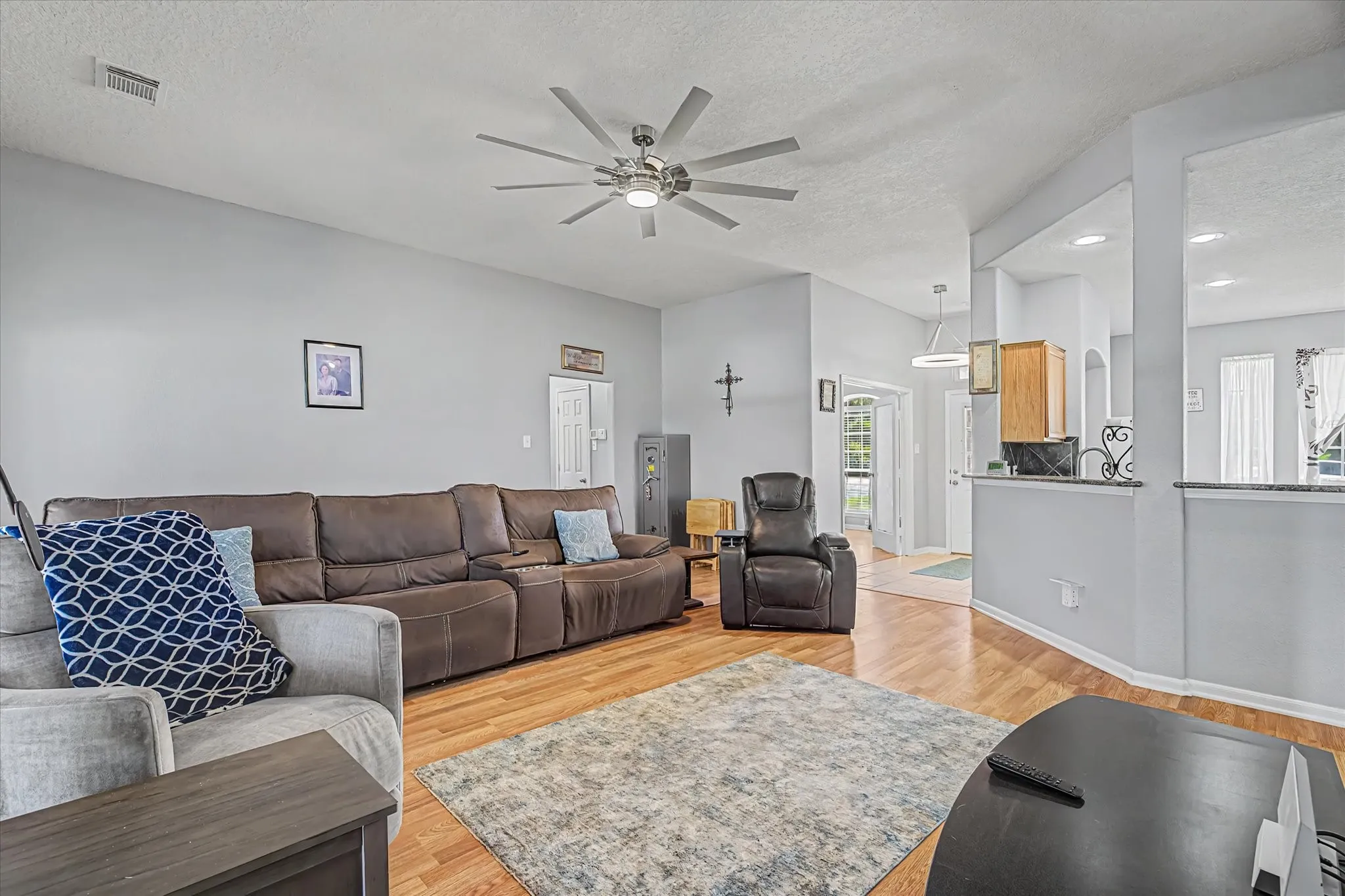 Vaulted ceiling, ceiling fan with integrated lighting, half-wall with granite countertop and recessed lighting