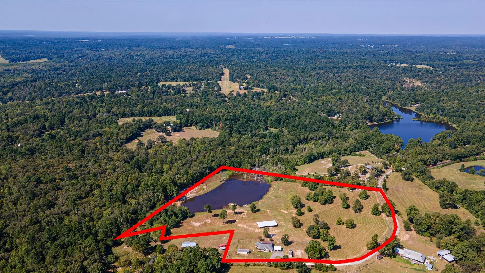 Aerial View of 17.82 acre property. Expansive acreage featuring a private pond, multiple structures, and mature trees.
