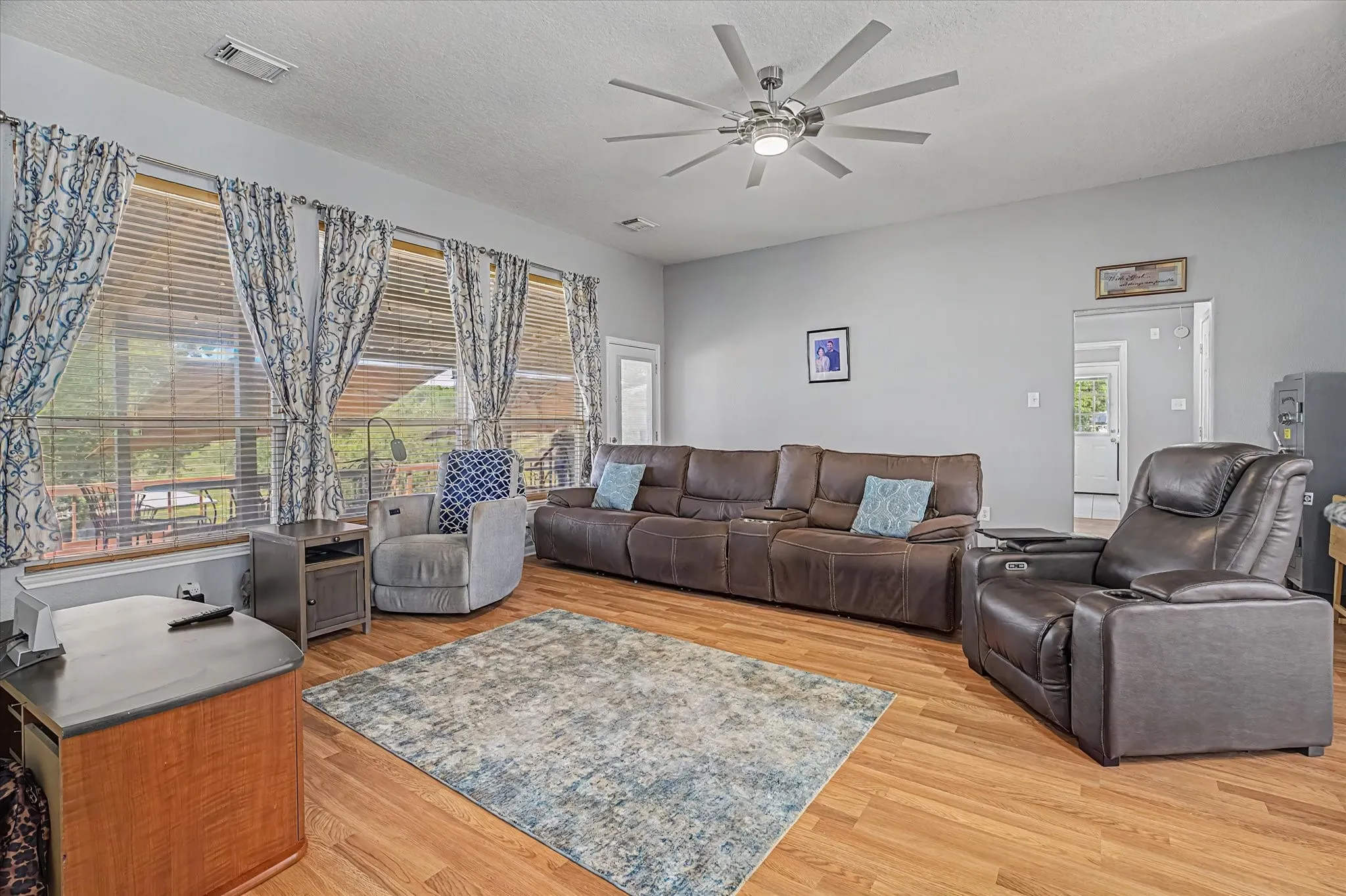Expansive windows with blinds overlooking beautiful back of property.