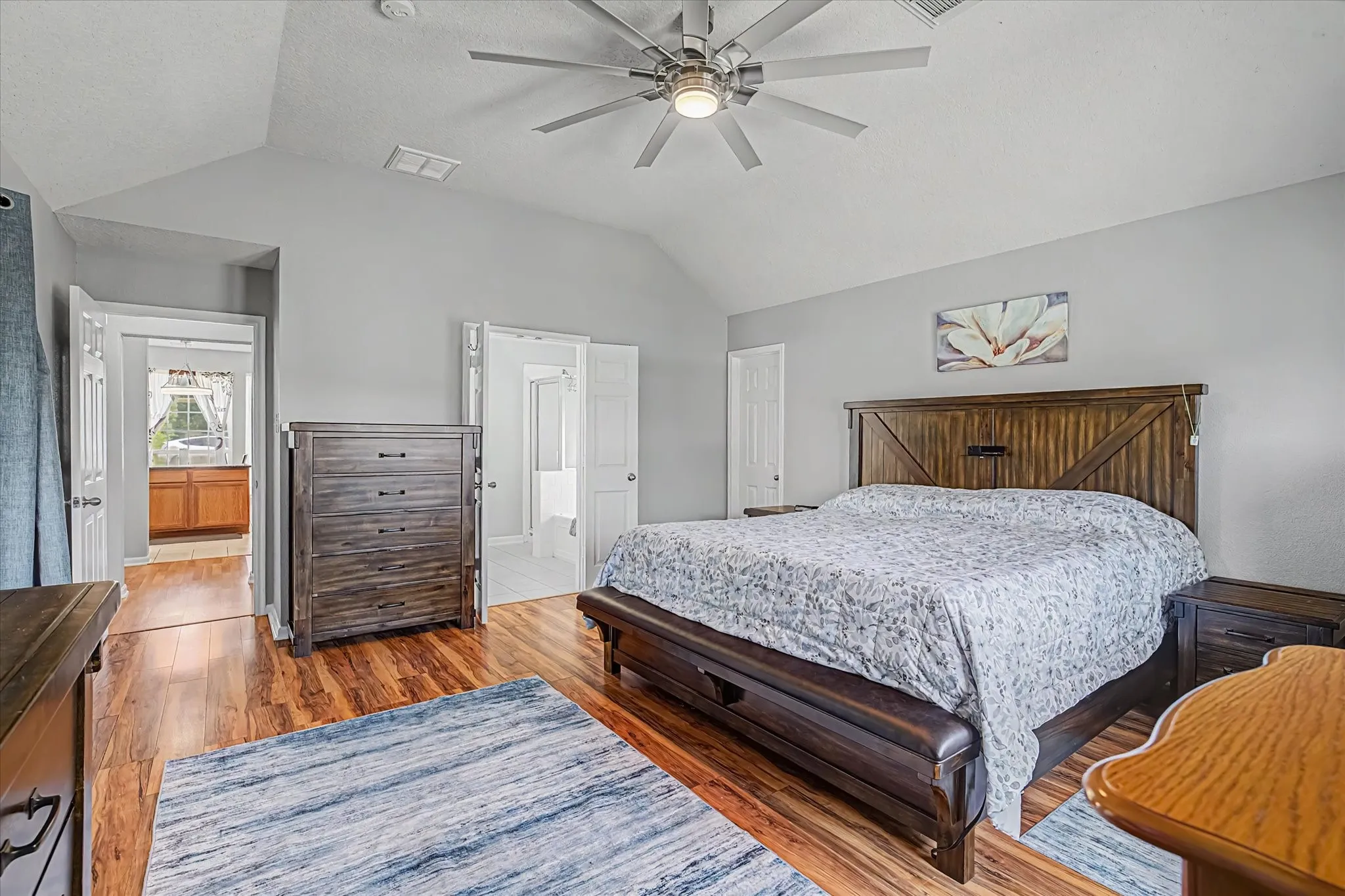 Large primary suite w/ vaulted ceiling with ceiling fan and primary on-suite bath