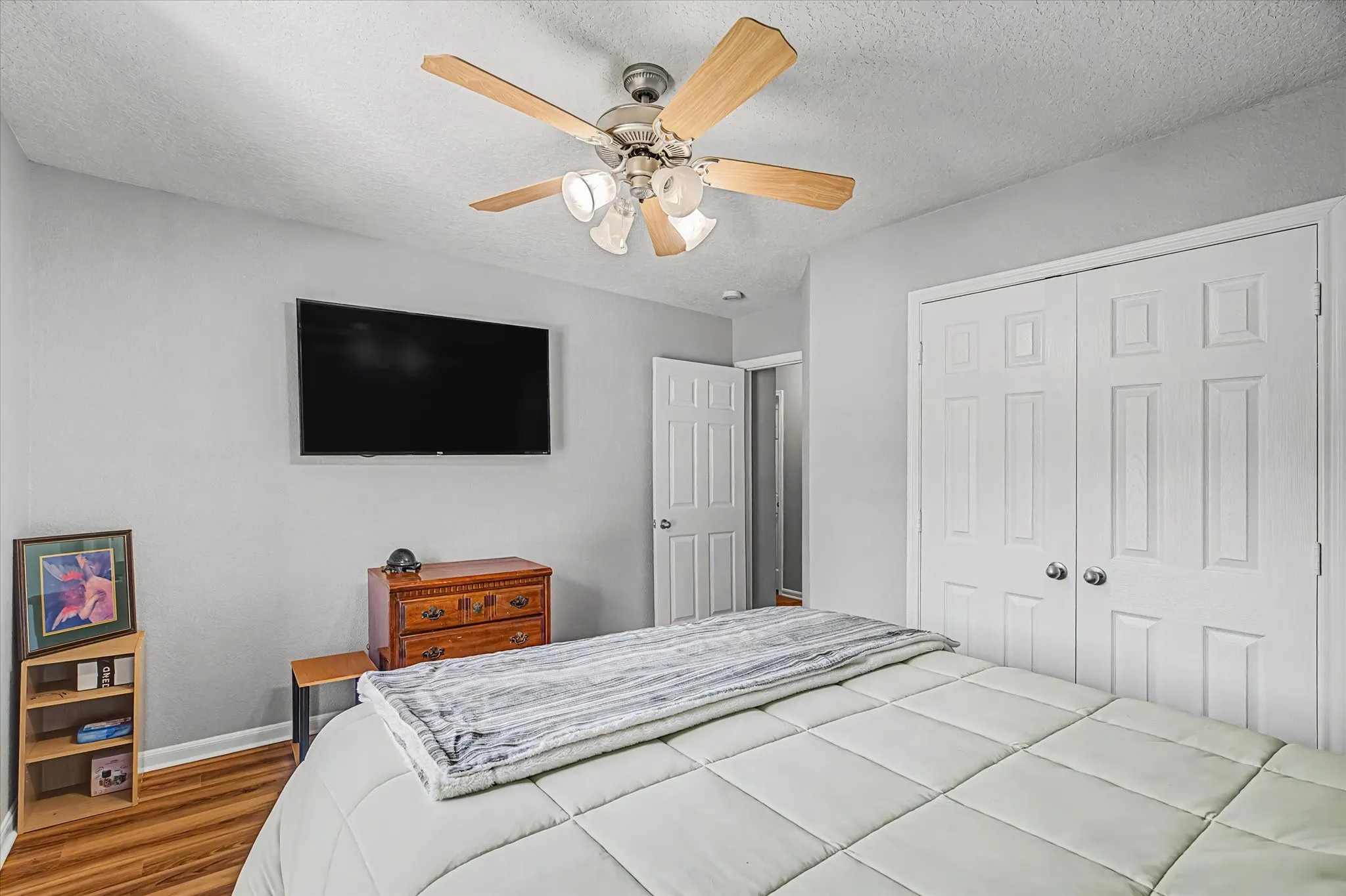 3rd bedroom w/ ceiling fan with integrated lighting, wall-mounted display, and paneled bi-fold closet doors