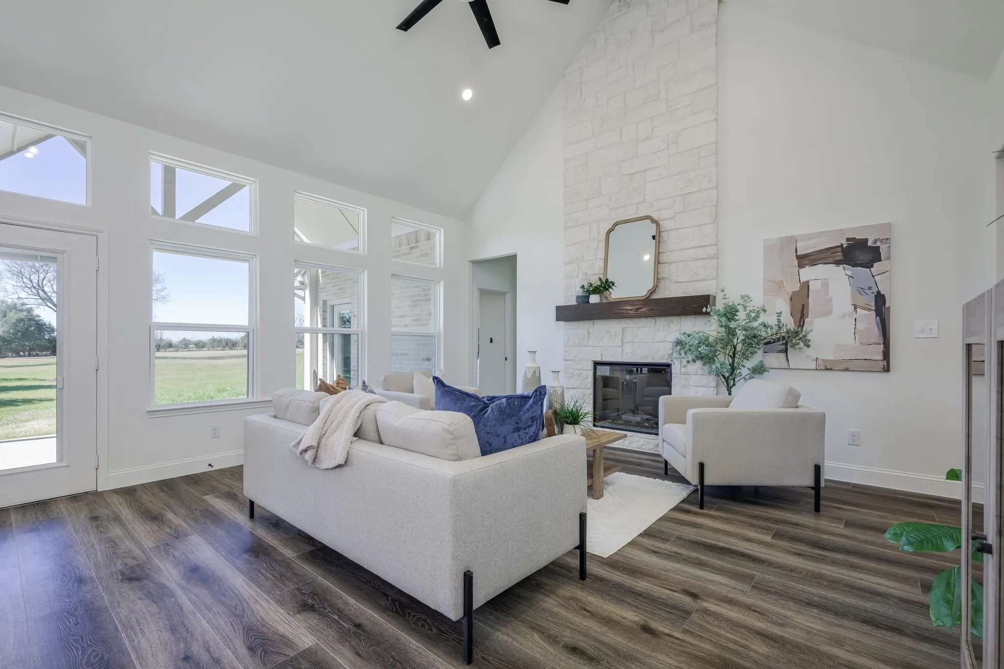 Beautiful living room featuring a stunning floor-to-ceiling stone fireplace and an abundance of windows that fill the space with natural light.