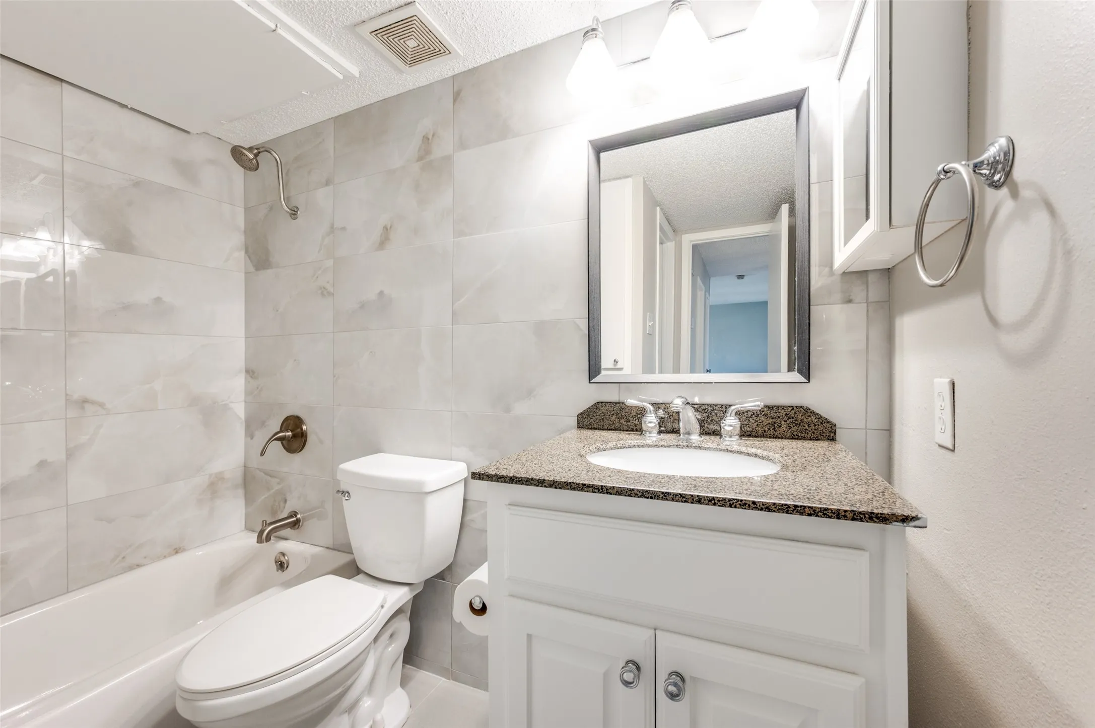 White vanity with a stone-finish countertop and an undermount sink