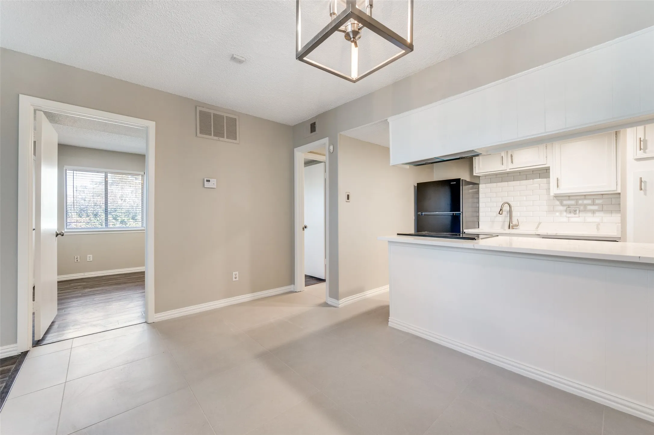 Kitchen featuring white cabinetry, subway tile backsplash, and a black appliance package