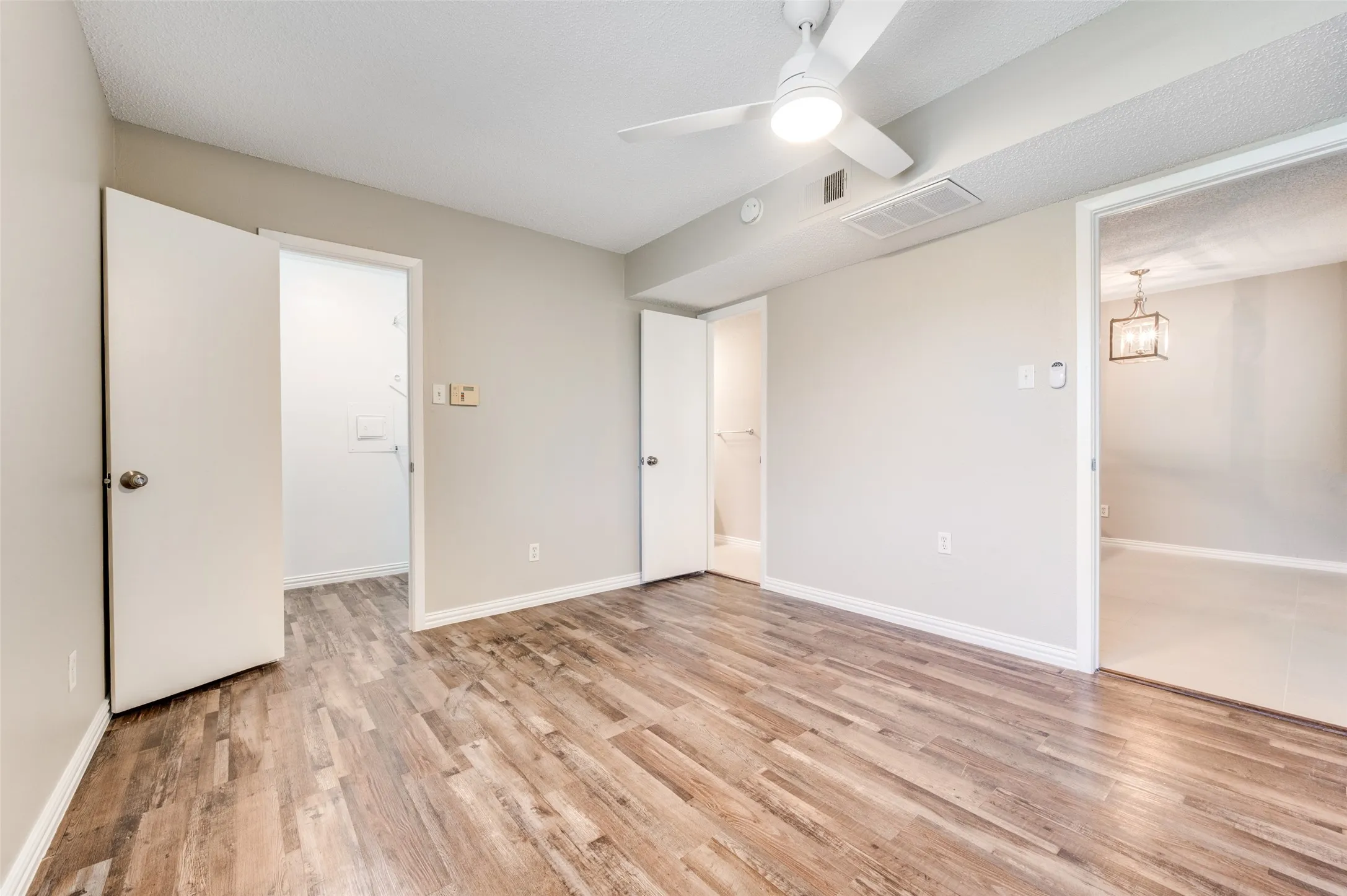 Wood-finish flooring, neutral wall tones, ceiling fan, and white trim throughout