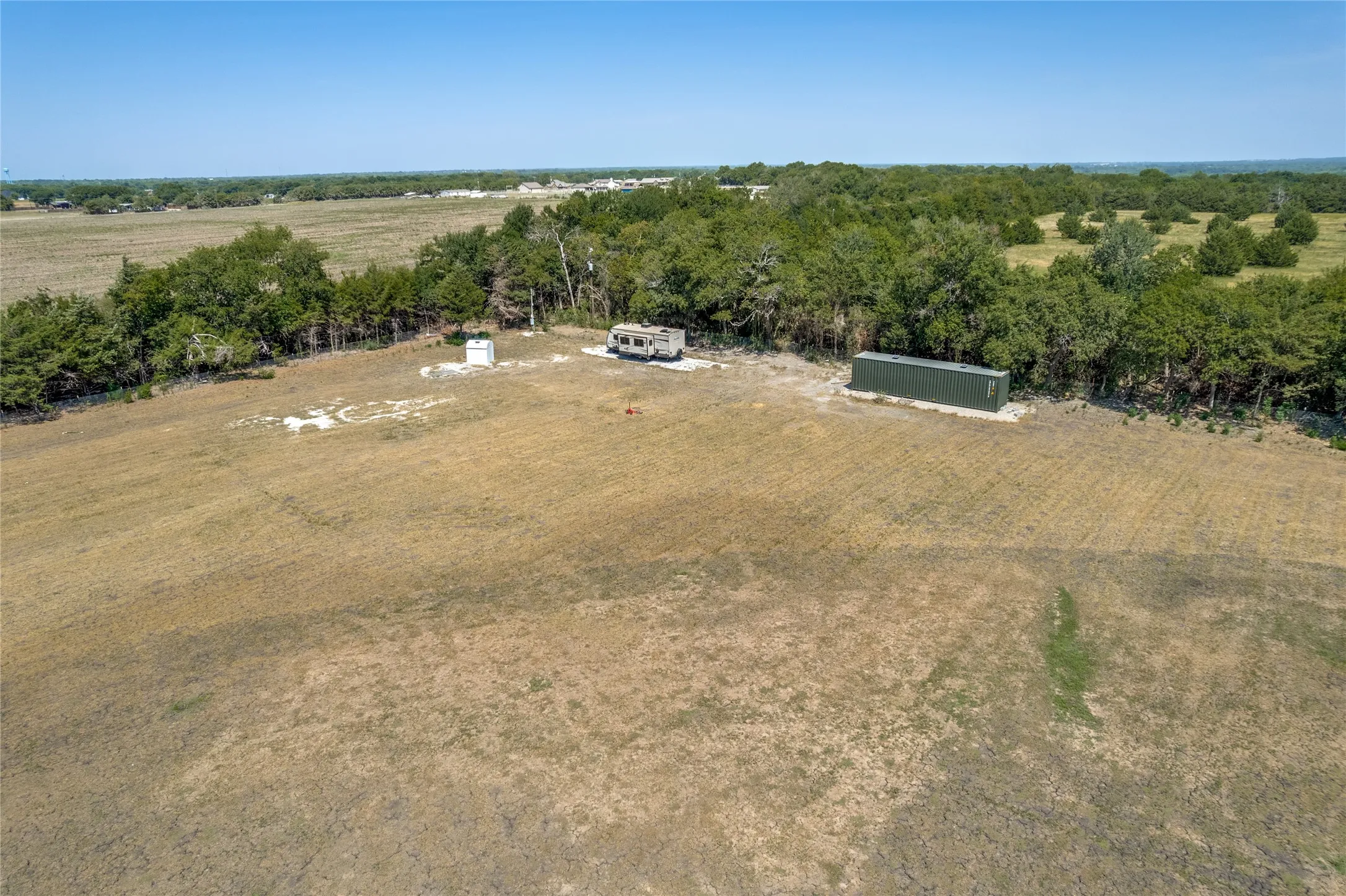Expansive open land with varied vegetation and distant tree lines