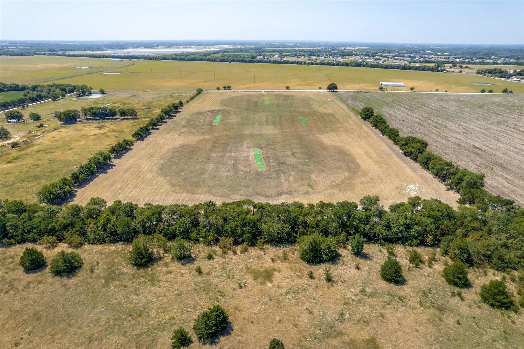 Expansive agricultural land featuring a tree-lined perimeter and cultivated fields