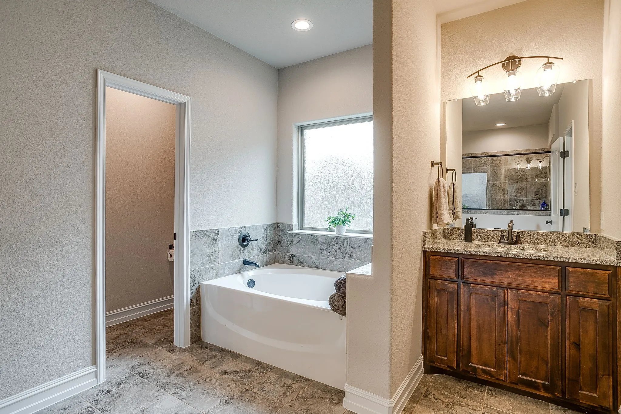 Built-in soaking tub with dark bronze fixtures and tiled surround