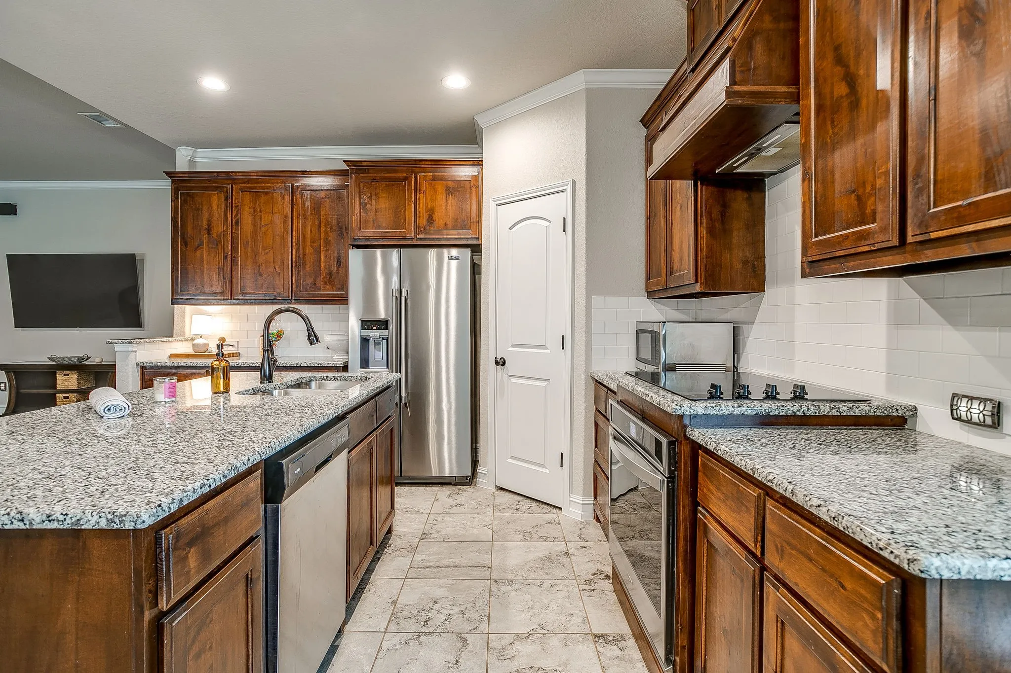 Kitchen featuring granite countertops, wood cabinetry, stainless steel appliances, and tile flooring