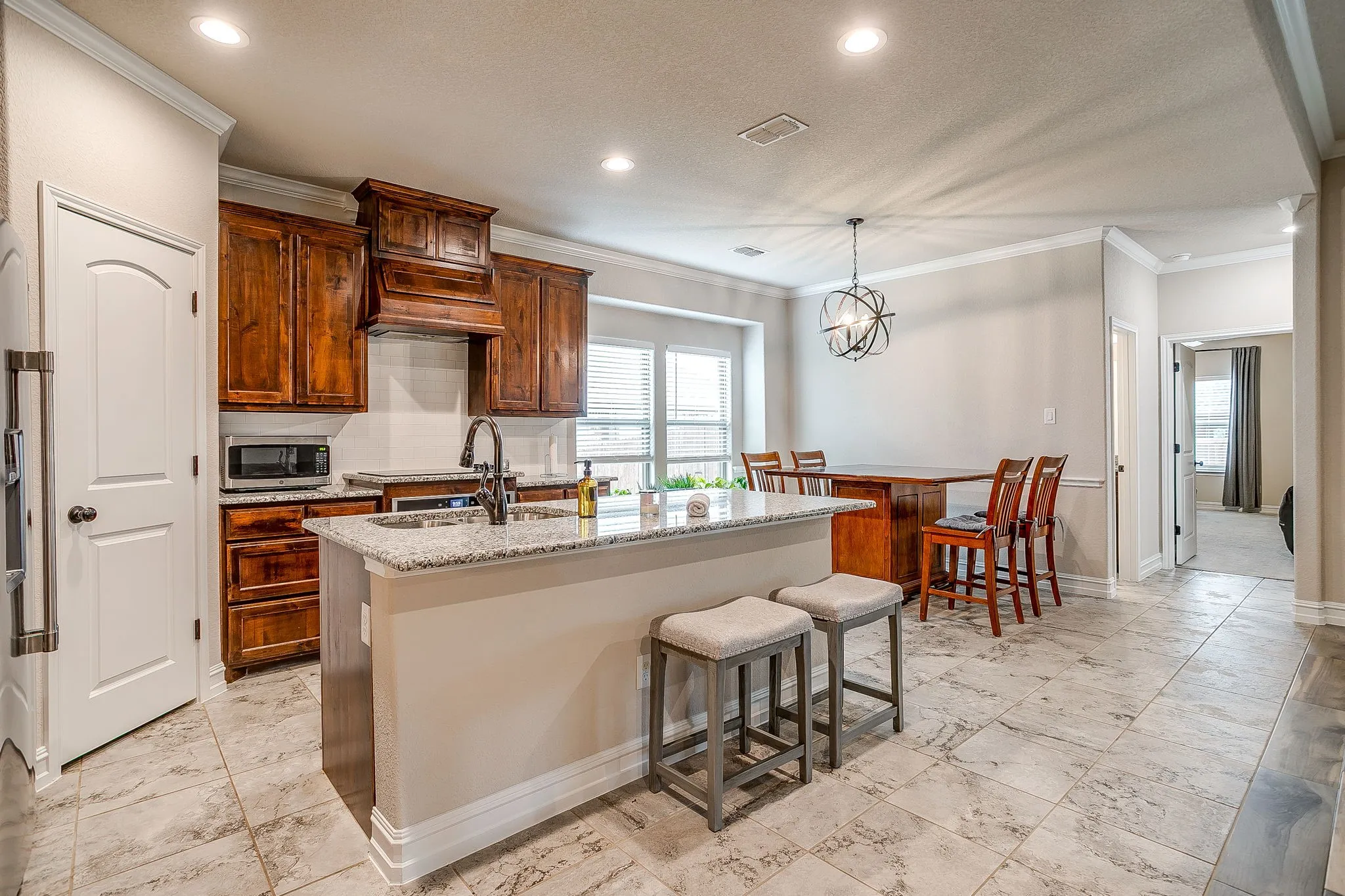 Kitchen island with granite countertop, wood cabinetry, recessed lighting, tile flooring, and a decorative pendant light fixture