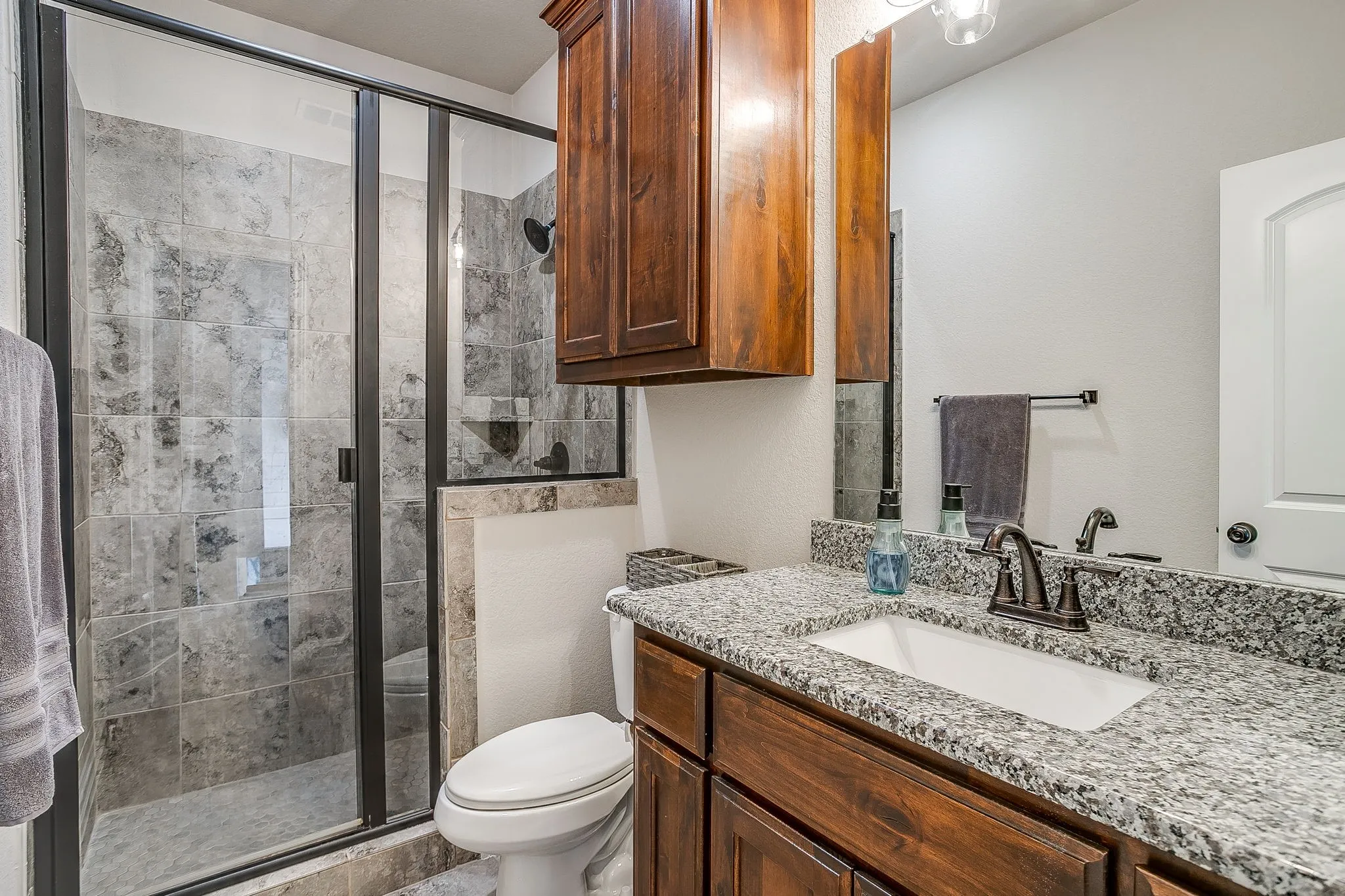 Walk-in shower with dark-framed glass enclosure, tiled walls, and a built-in shower niche