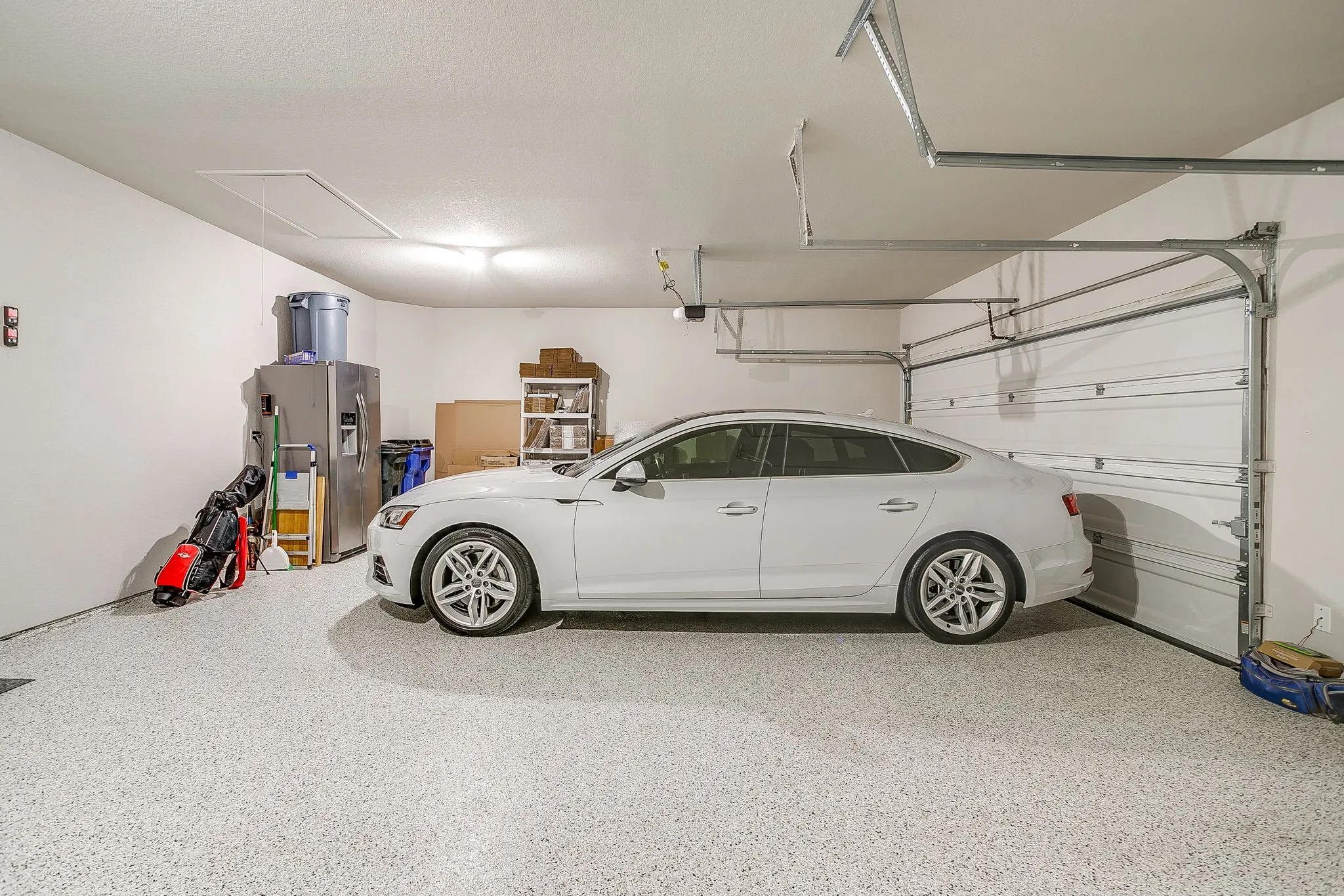 Spacious garage featuring a durable epoxy floor coating, white walls, and a ceiling-mounted access panel