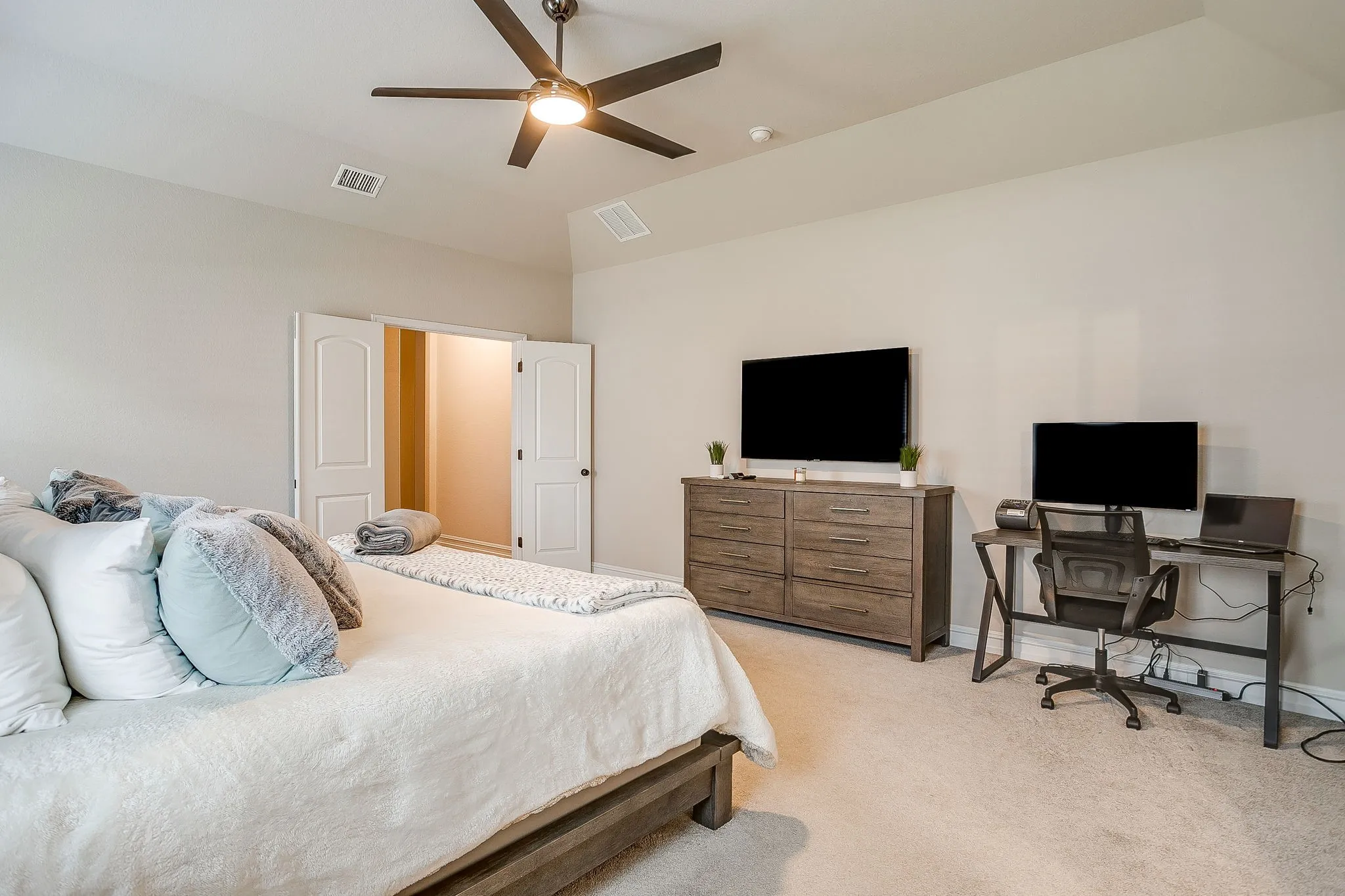Vaulted ceiling with a ceiling fan, light-toned carpeting, double closet doors, neutral wall colors, and a built-in closet space