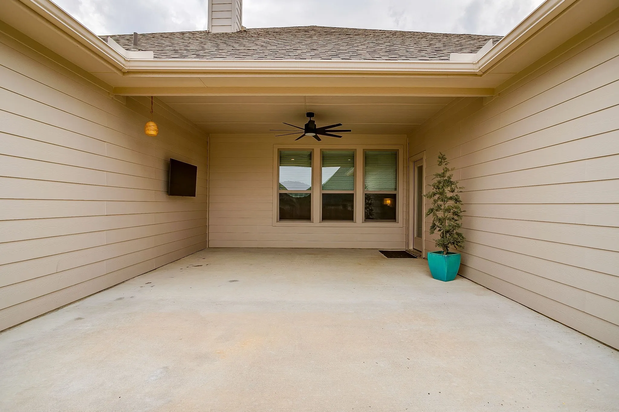 Covered patio with a mounted television, ceiling fan, and recessed lighting