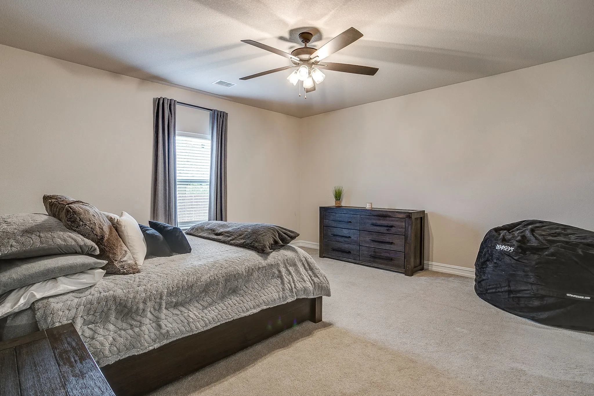Ceiling fan with integrated lighting, window with blinds and drapes, light-colored walls, and carpet flooring