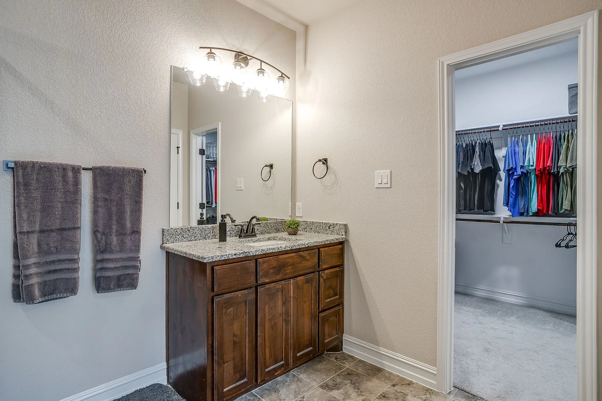 Vanity featuring a granite countertop, wood-finish cabinetry, and an attached mirror