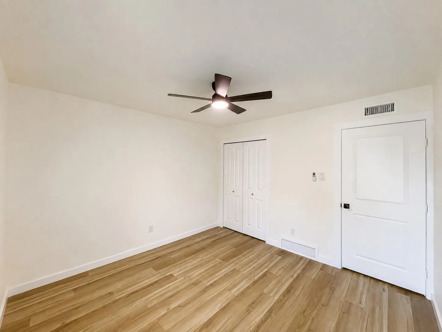 Wood-finish flooring, white walls, ceiling fan with integrated lighting, and bi-fold closet doors