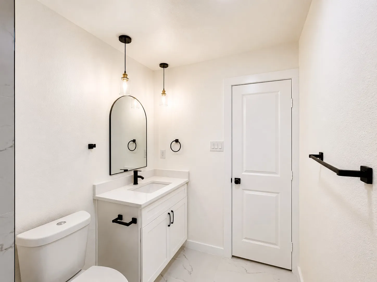 White vanity with a solid surface countertop, undermount sink, and matte black fixtures
