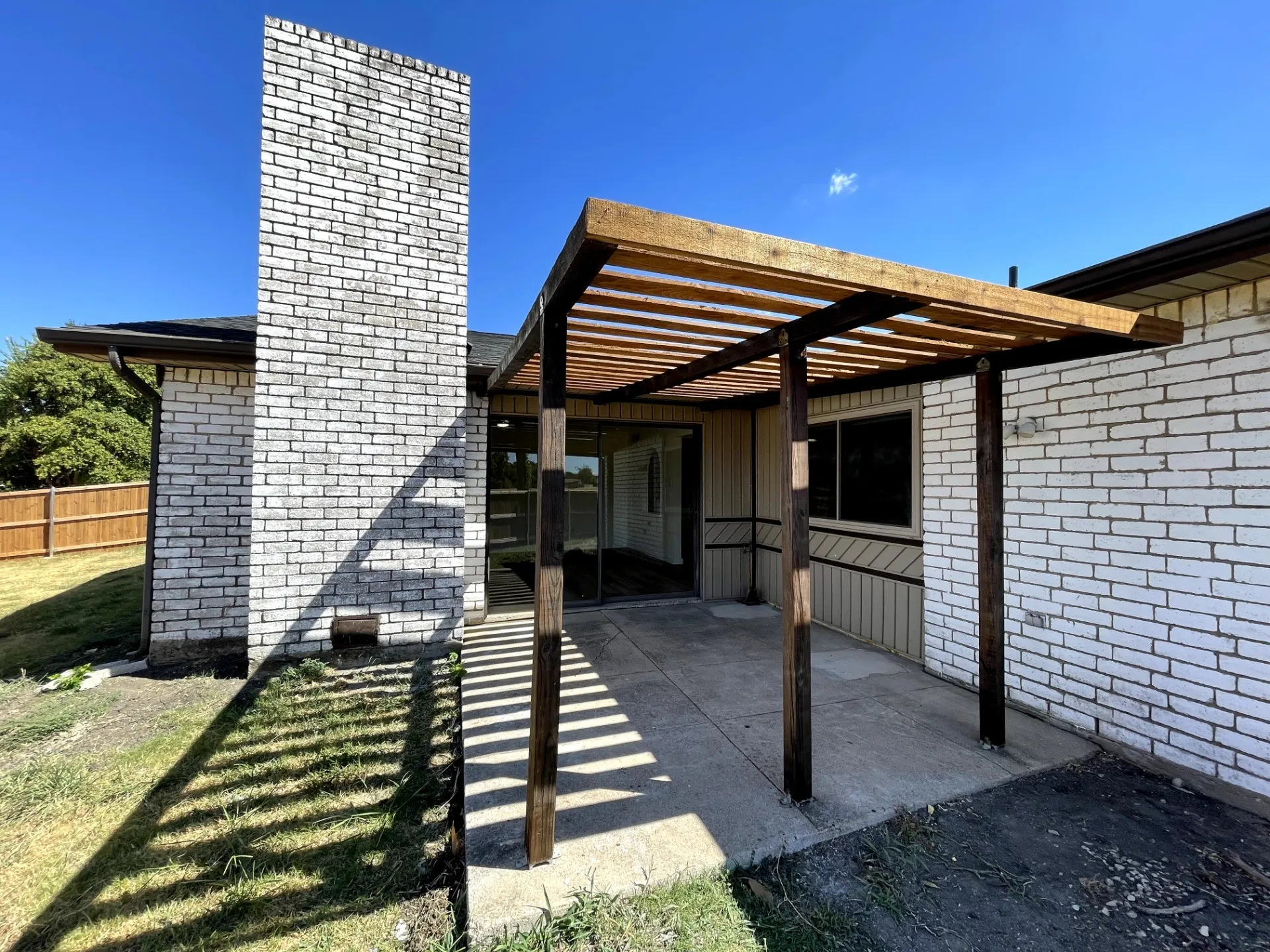 Brick exterior with a wood pergola covering a concrete patio