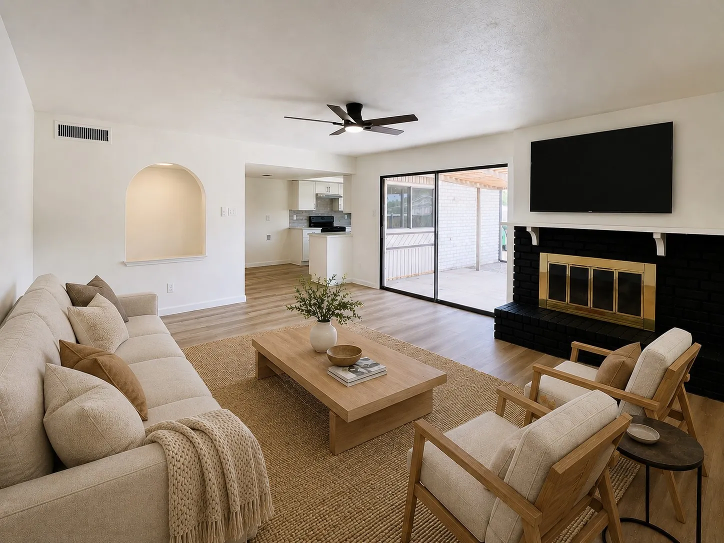 Spacious living area featuring wood-finish flooring, a contemporary ceiling fan, and a built-in fireplace with a hearth