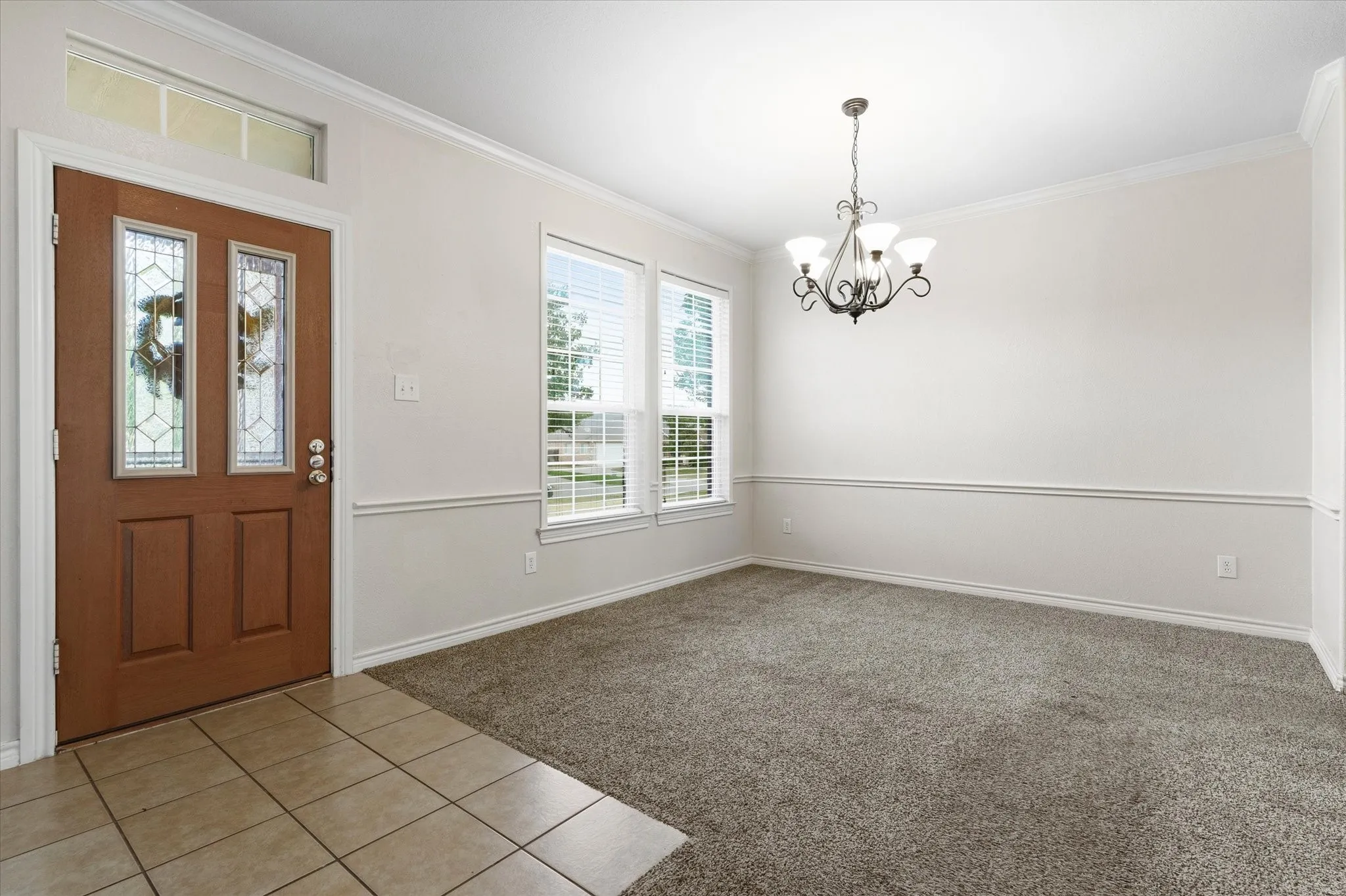 Entryway featuring a wood-panel door with decorative glass inserts, transom window, and tile flooring