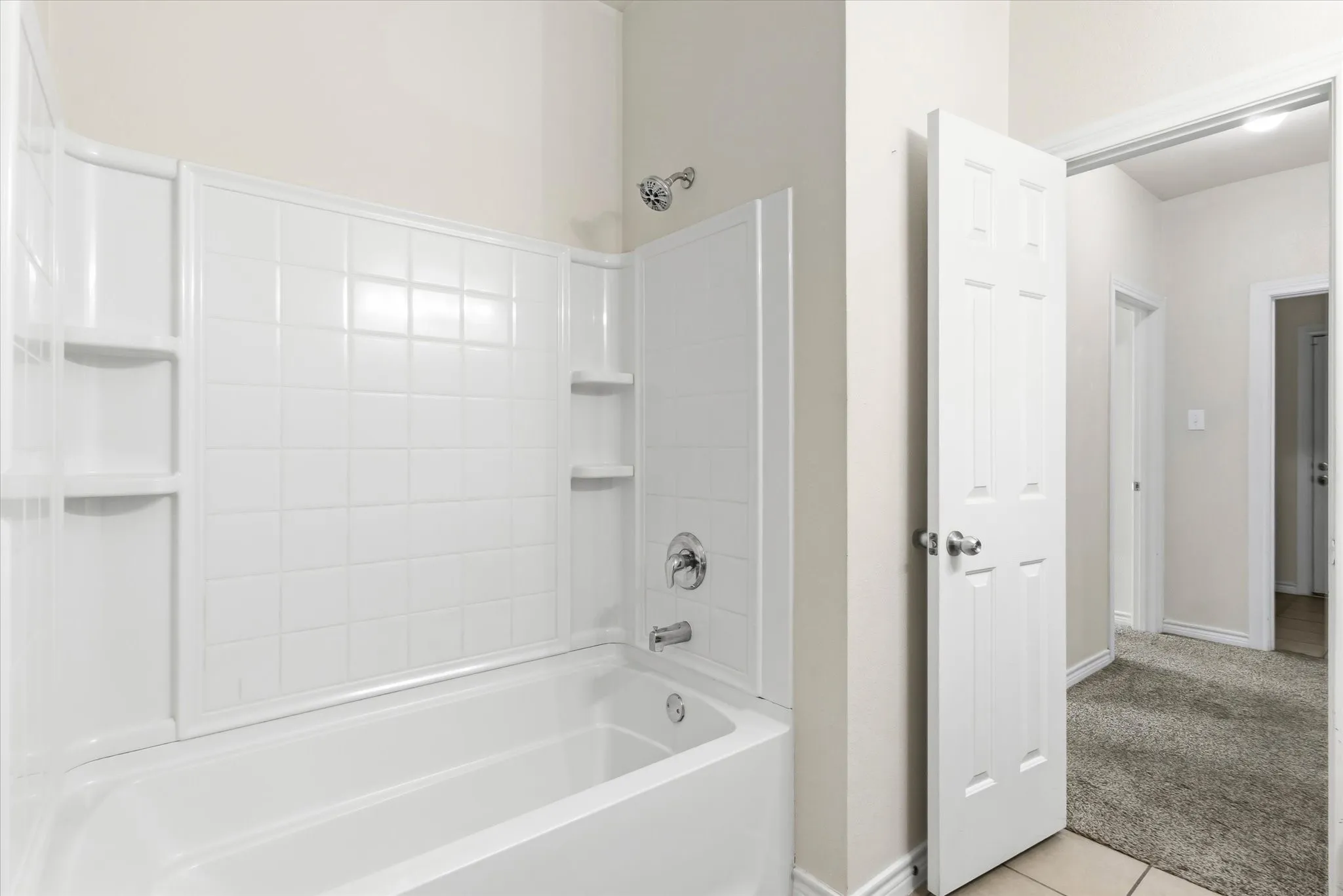 Secondary Bathroom white acrylic tub with integrated shower surround and built-in shelving