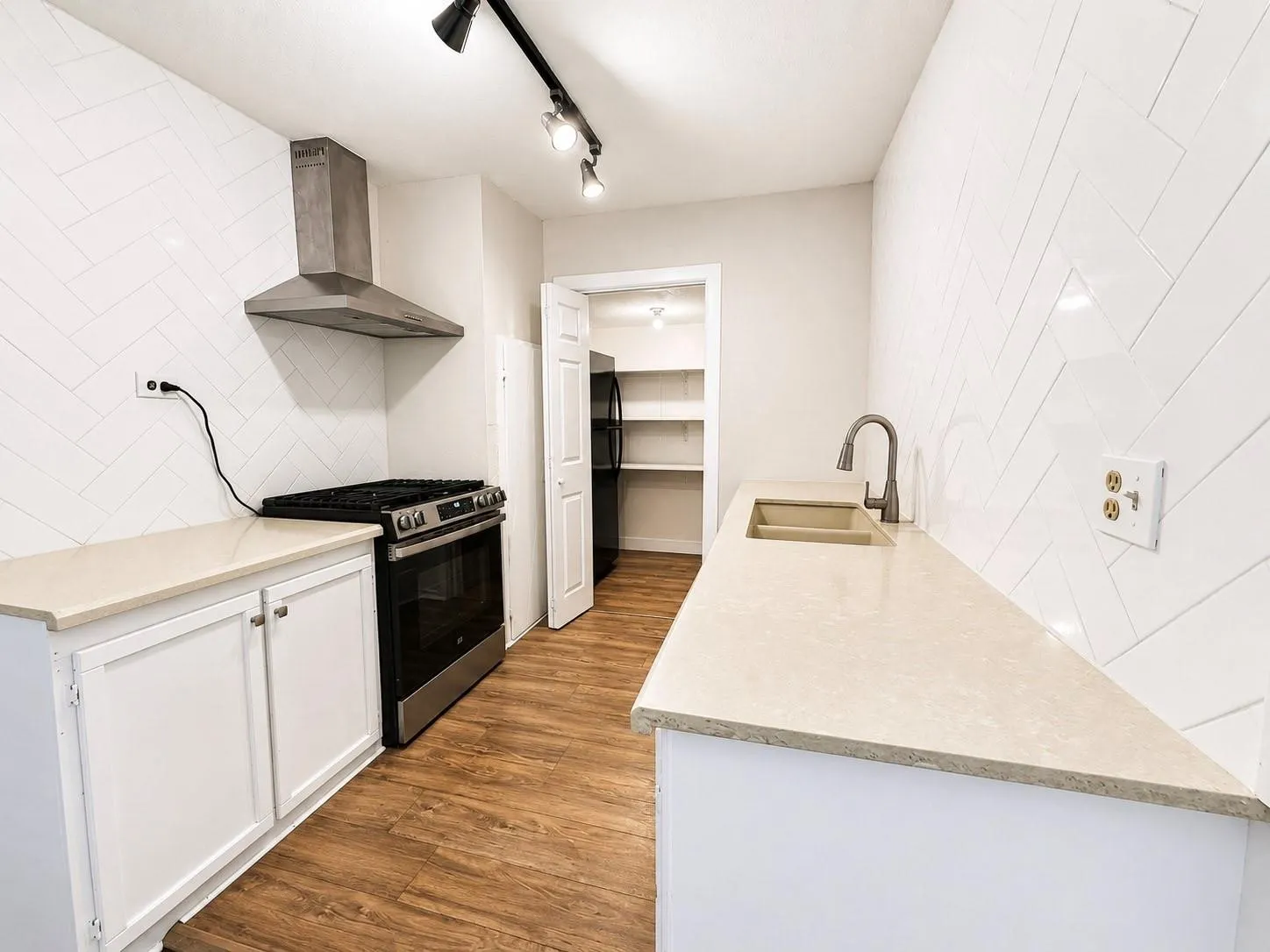 White shaker-style cabinetry with light countertops, stainless steel range with matching vent hood, and wood-finish flooring