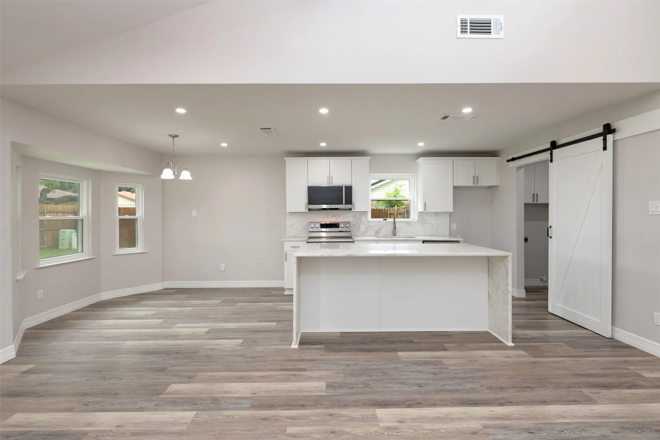 Open-concept living area with wood-finish flooring, recessed lighting, and a kitchen island with stone countertops